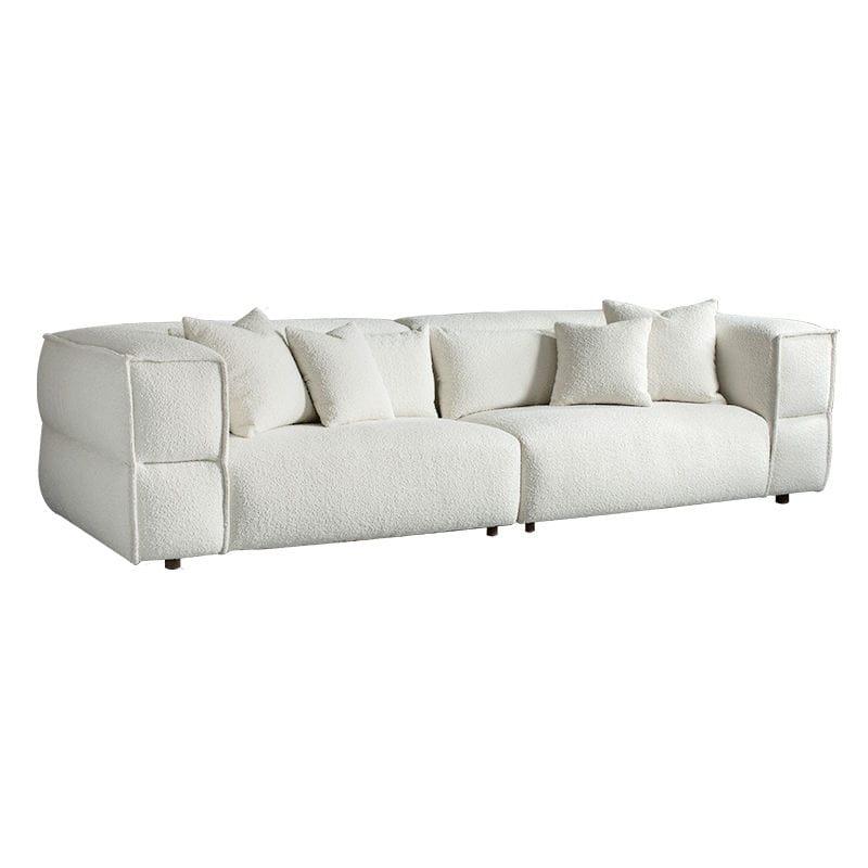 Low-profile white boucle sectional sofa with deep cushioned seats, rounded block arms, four matching throw pillows and short dark wooden legs on a white background.