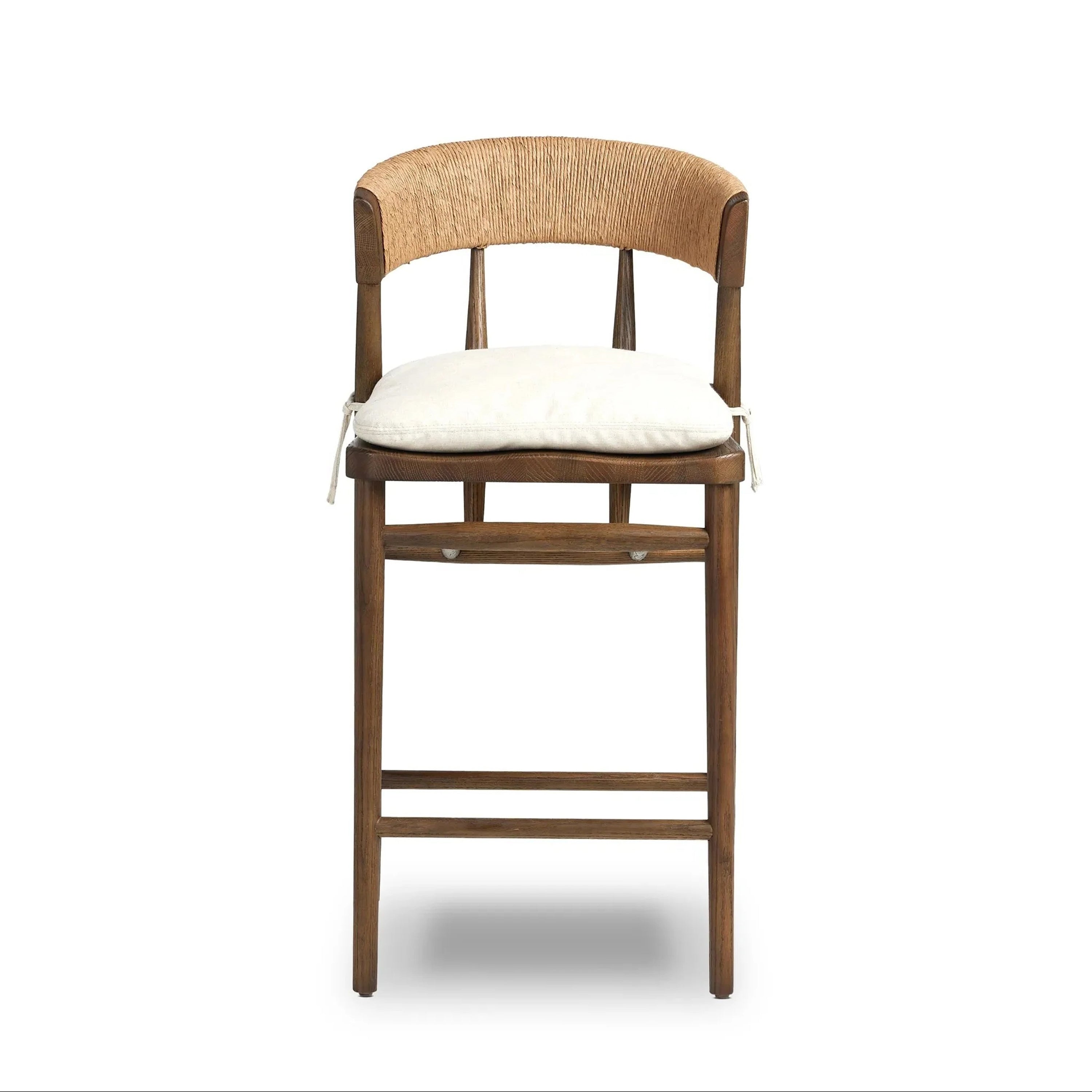 Front view of a natural wood counter stool with a curved rope-wrapped C-back, off-white tied cushion seat, slender spindle supports and a two-bar footrest in a rustic farmhouse style.