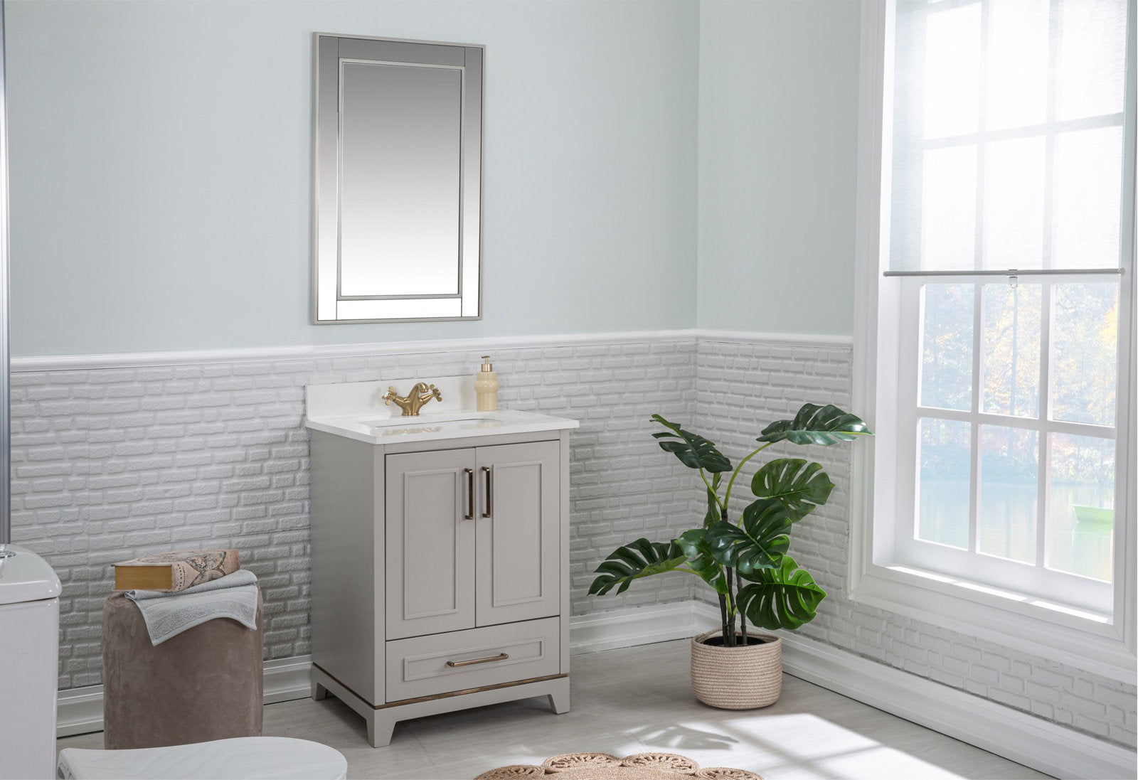 Modern solid wood single-sink bathroom vanity in a stone finish with a stone top and ceramic sink, paired with a gold faucet and mirror, shown freestanding in a light bathroom beside a potted plant and sunlit window.