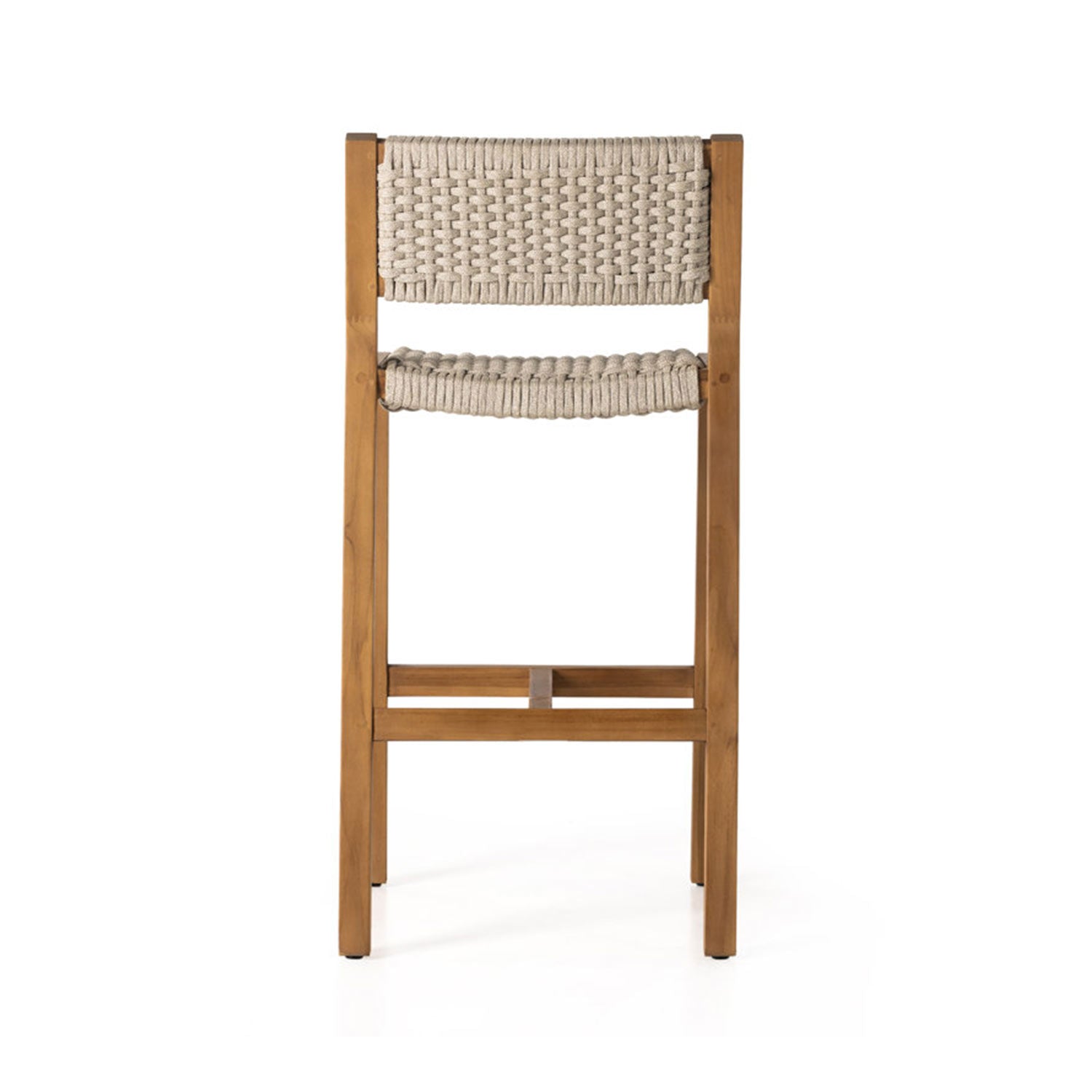 Rear view of an armless outdoor bar stool with a natural teak frame and beige woven rope seat and back, square legs and built-in footrest in a coastal solid-wood design.
