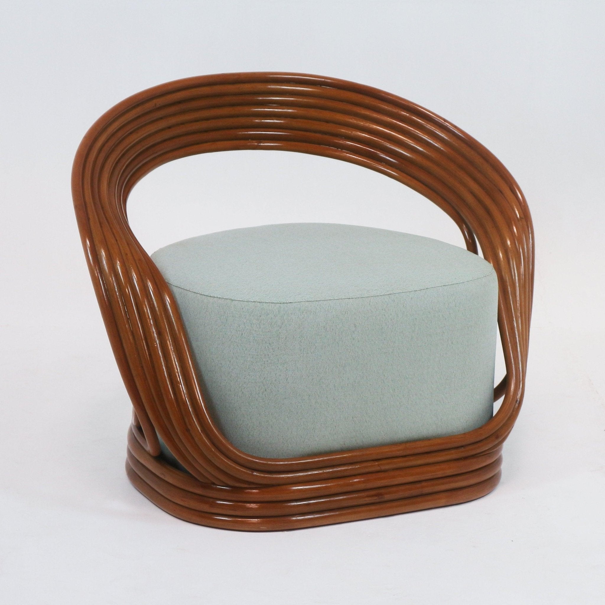 Mid-century modern lounge chair with a continuous curved brown cane frame surrounding a round light-green fabric-upholstered seat cushion.
