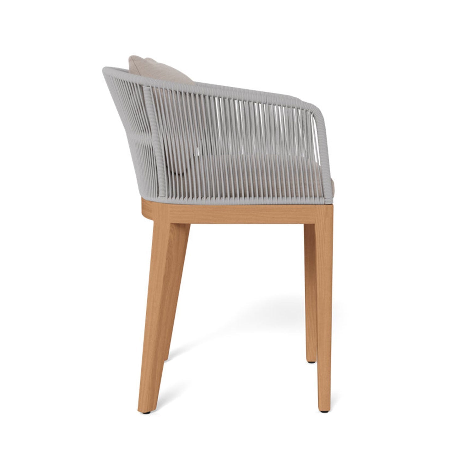 Side view of a coastal-style outdoor bar stool with a teak wood frame, light gray rope-wrapped back and arms, and beige upholstered fabric seat and back cushions.