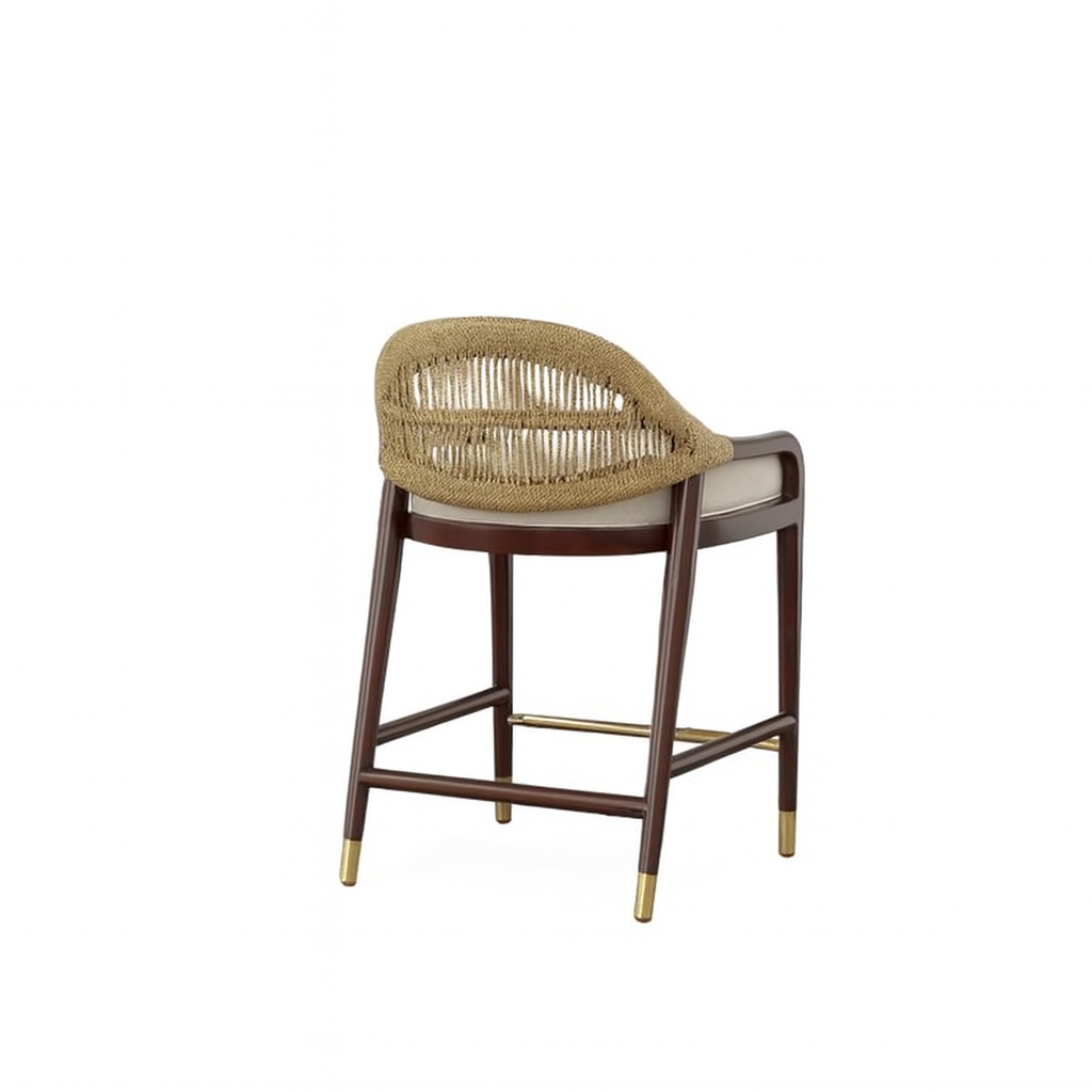 Rear three-quarter view of a teak-framed coastal counter stool with a natural rope-woven back, beige upholstered seat cushion, dark wood legs, and brass footrest and leg caps.