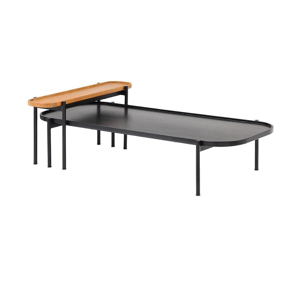 Modern twin coffee table set with a low black oval metal top and slim black metal legs, paired with a smaller mahogany teak tray top elevated above one end for a nested contemporary look.