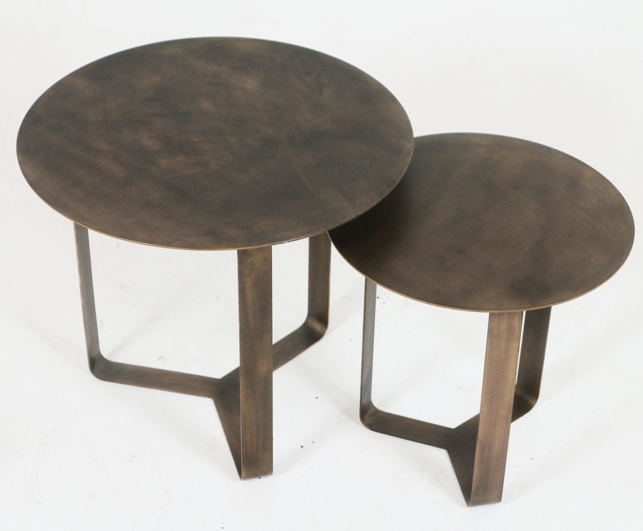 Set of two modern bronze metal side tables shown nested on a white background; each has a thin round top with a warm brushed bronze finish and minimalist U-shaped flat legs.