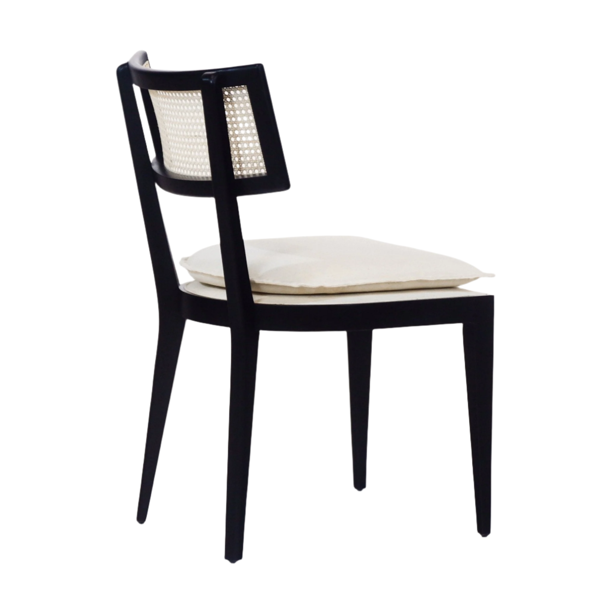Side view of a black wooden dining chair with a woven rattan backrest and a cream upholstered fabric seat cushion on tapered legs with a mid-century modern silhouette.