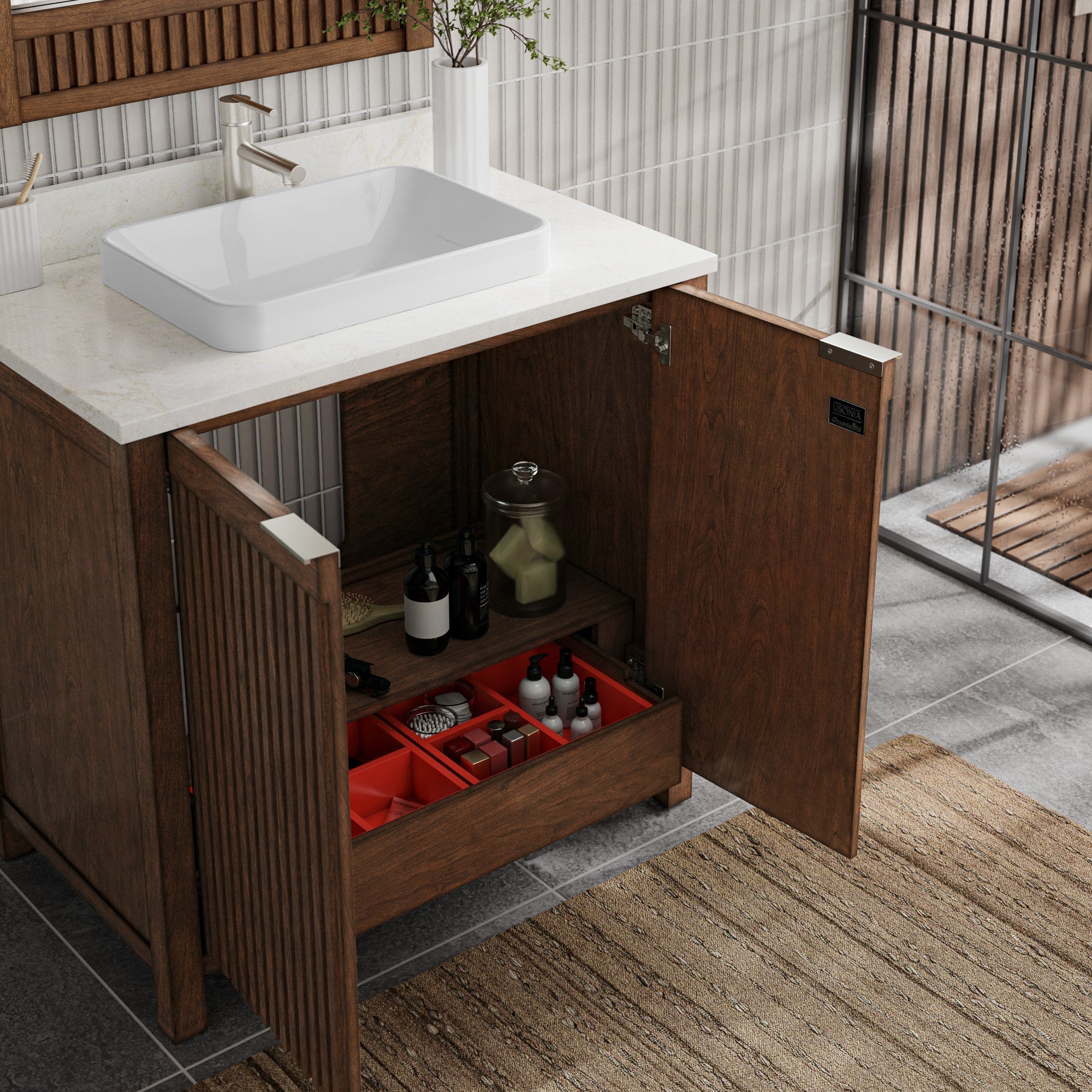 Freestanding fluted solid wood bathroom vanity with a stone countertop and rectangular white vessel sink; one door open to show interior shelf and a red compartment organizer with bottles and jars, brushed-metal hardware and rug below.