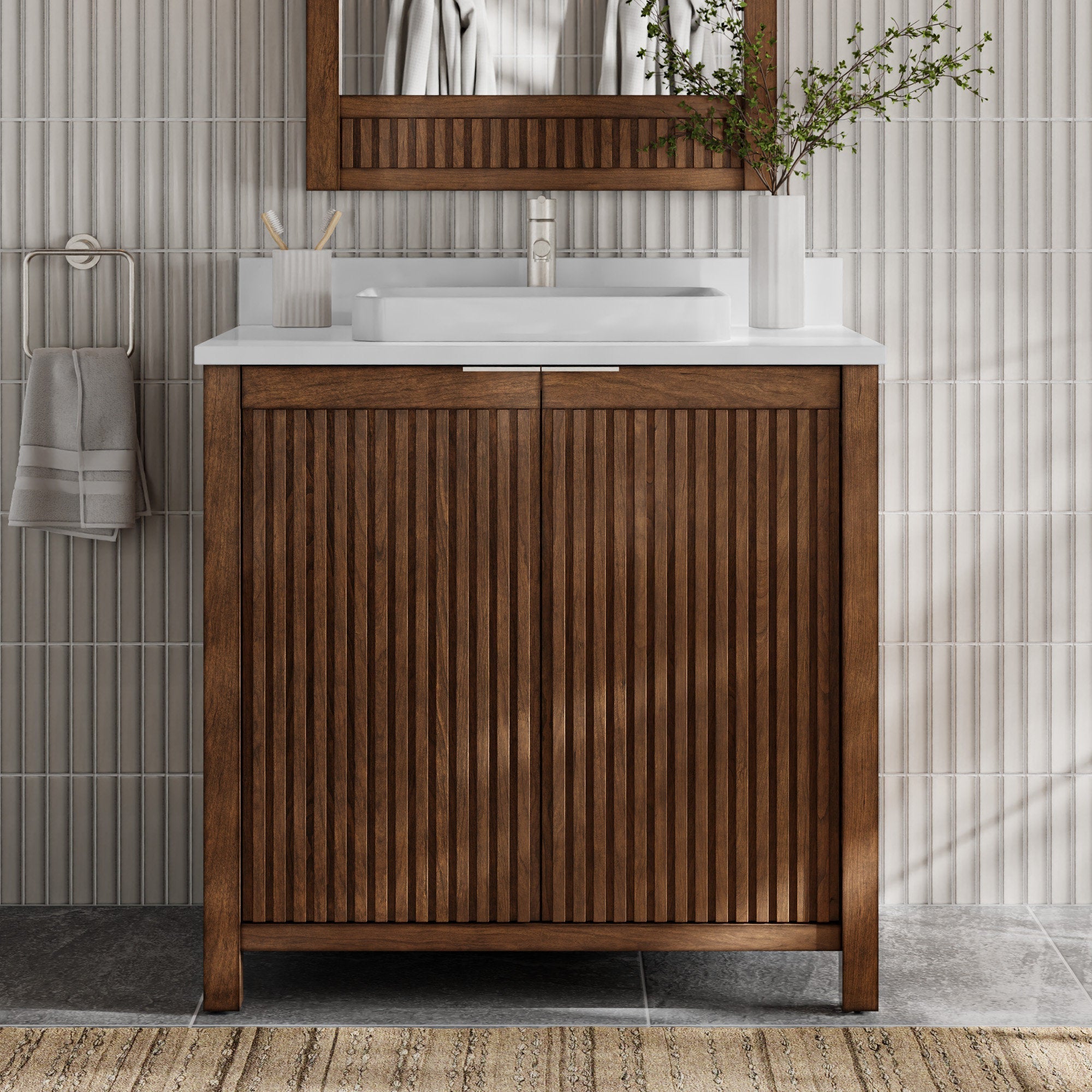 Freestanding modern fluted solid-wood bathroom vanity in warm brown with a stone top, white rectangular vessel sink and chrome faucet, matching fluted wood mirror, toothbrush cup, towel ring, and vase with greenery against ribbed tile.