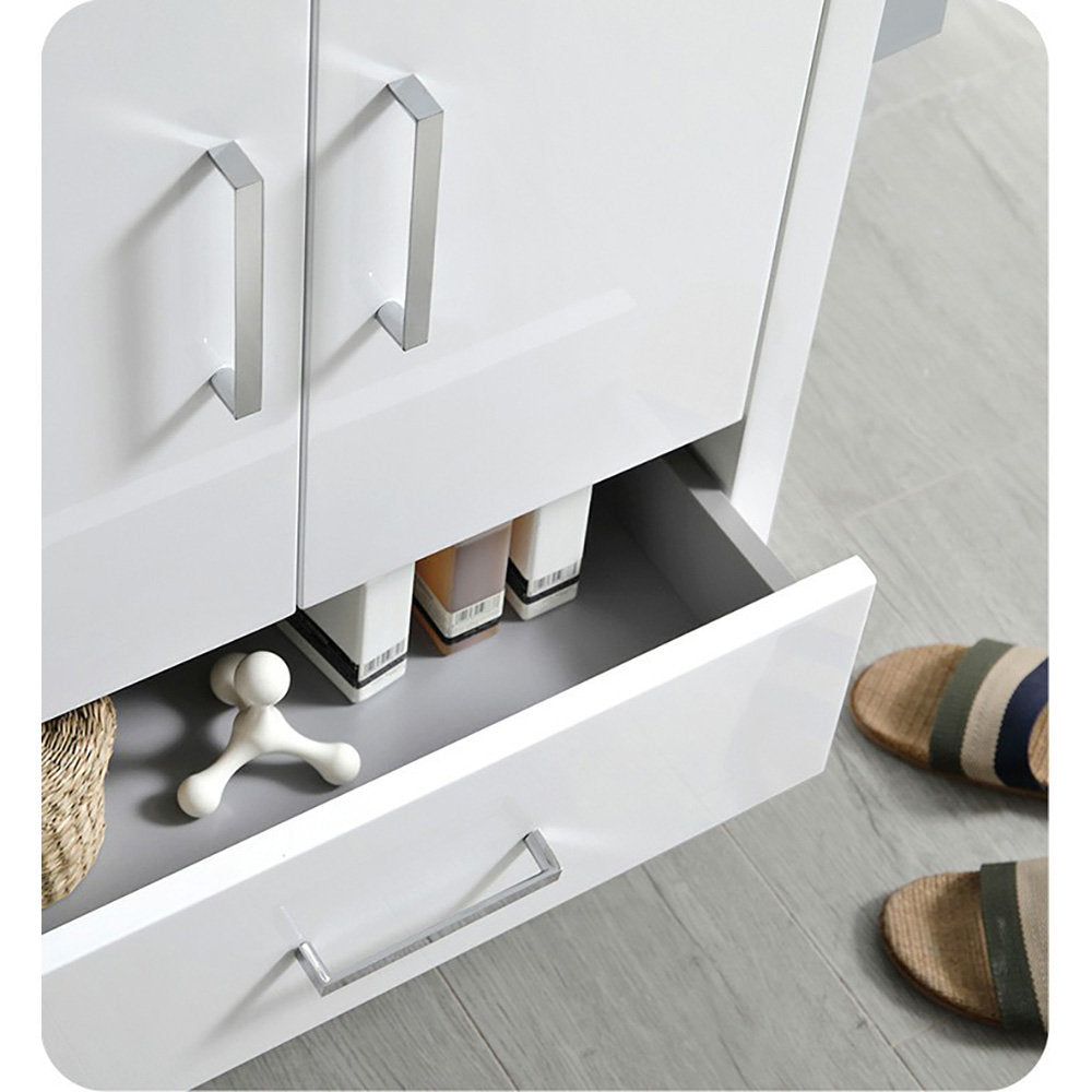 Close-up of a modern white solid-wood freestanding bathroom vanity with chrome handles; an open lower drawer reveals toiletries, a small decorative piece and a woven basket, set on gray tile floor beside woven sandals.