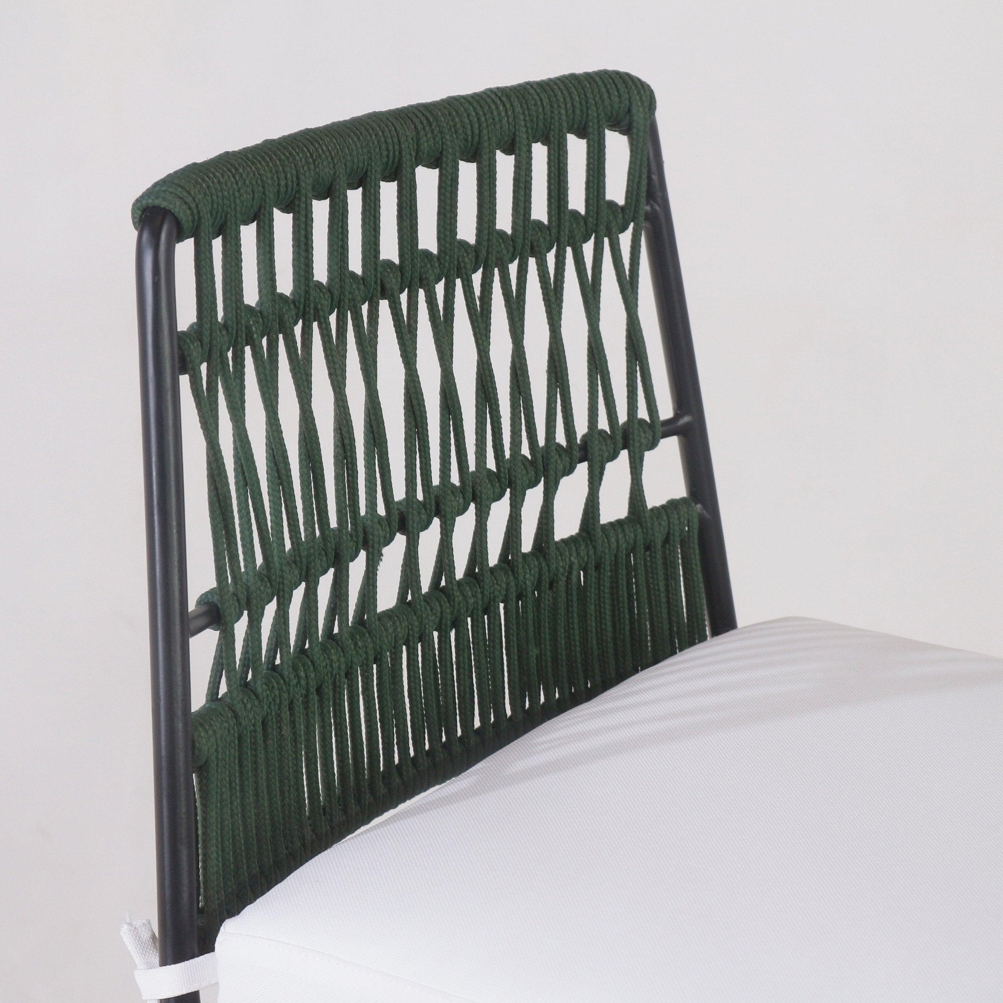 Close-up of an outdoor bar stool showing a dark green rope-woven back on a black metal frame and a white fabric seat cushion, highlighting the knotted weaving detail and tubular metal legs.
