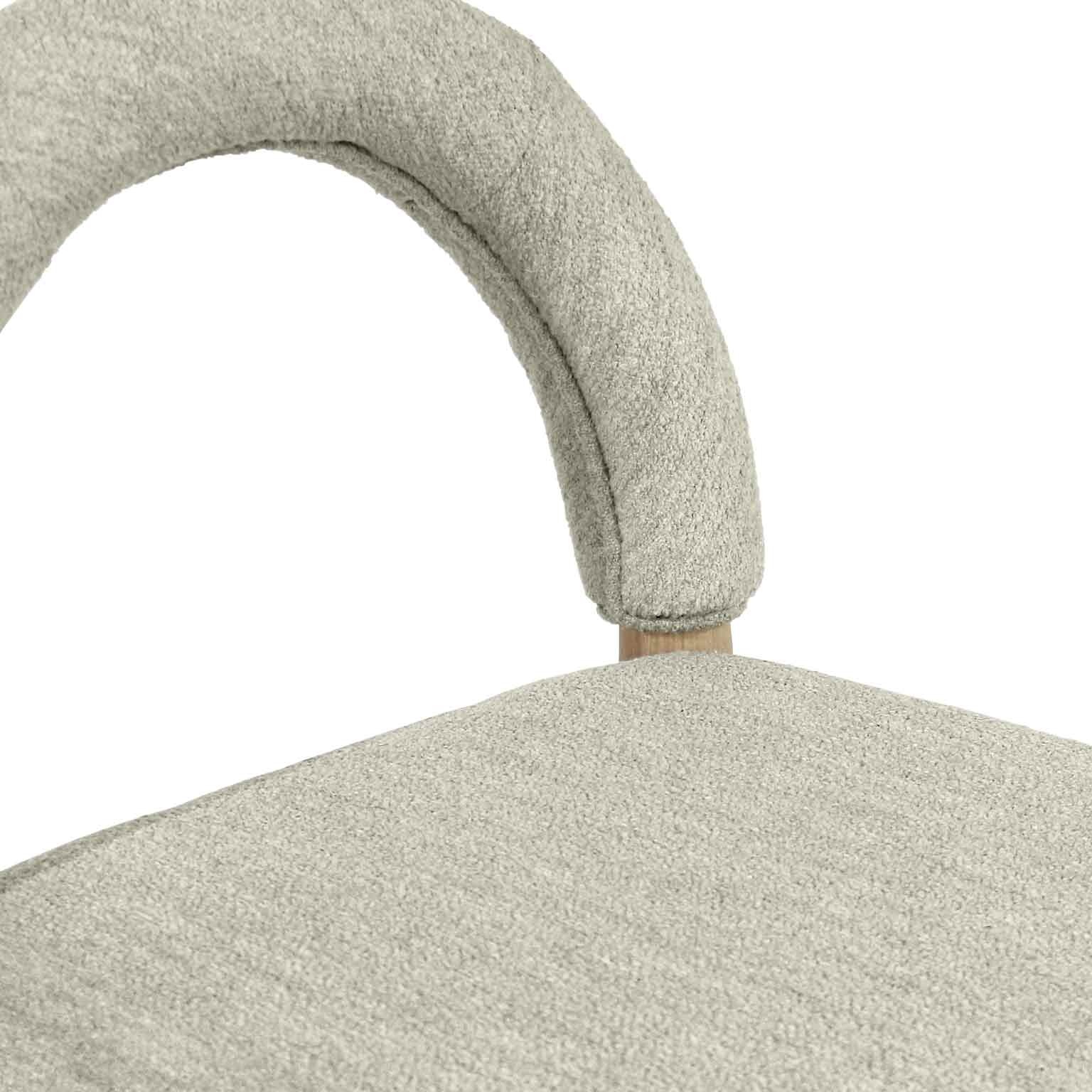 Close-up of a beige-taupe bouclé upholstered seat and arched backrest showing textured fabric and a natural oak leg.