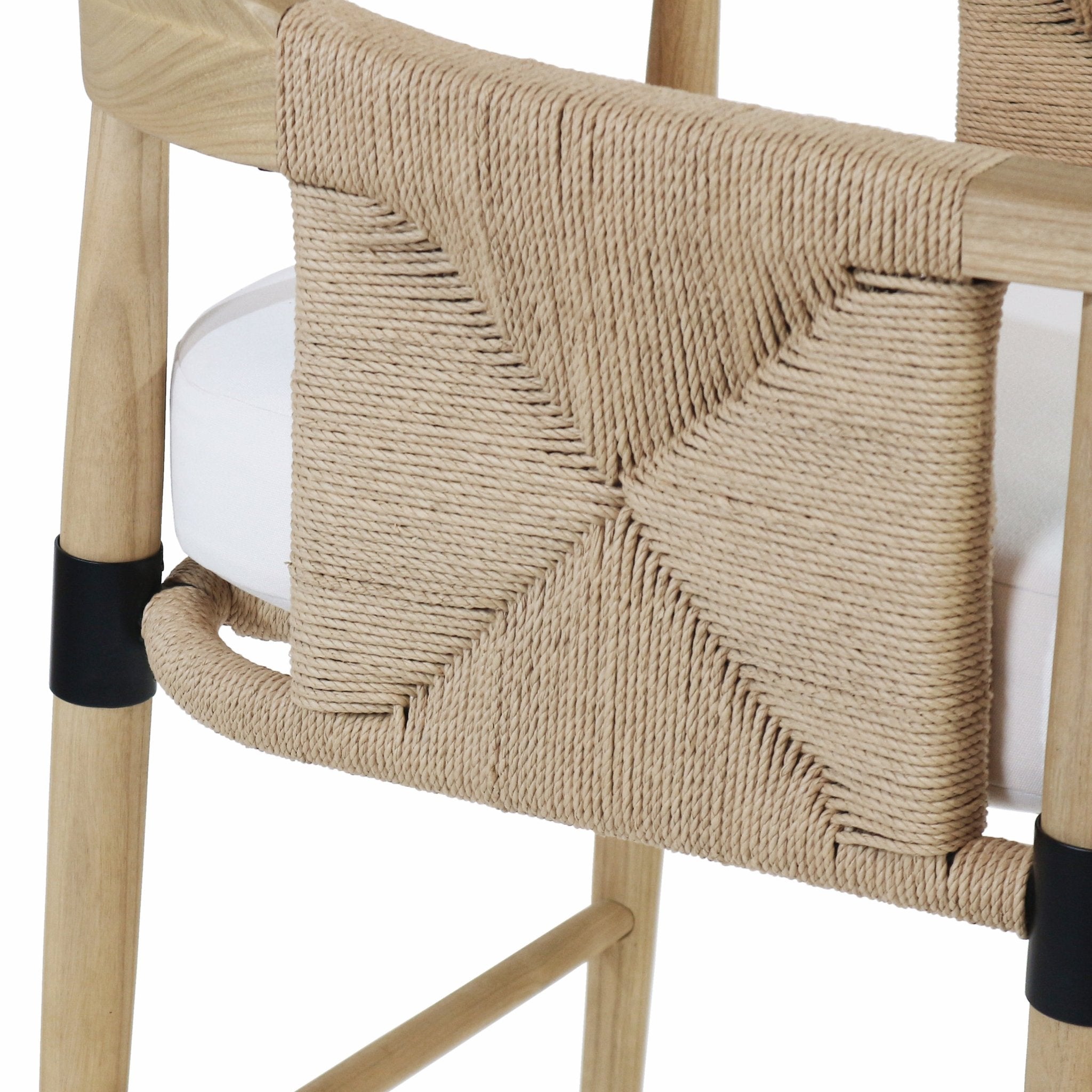 Close-up of a natural rope-woven backrest on a light natural wood frame, showing the braided X-pattern weave, hand-wrapped footrest, white upholstered seat cushion, and a black metal leg sleeve.