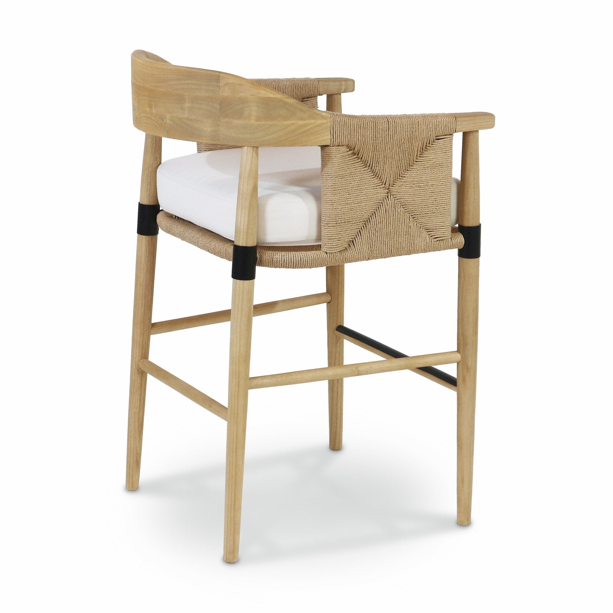 Natural wood counter-height stool with woven rope back and sides, white upholstered seat cushion, tapered legs and black metal leg bands with a black metal footrest.