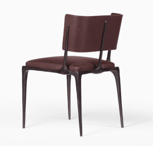 Rear three-quarter view of a modern brown leather-upholstered dining chair with a cushioned seat and curved backrest supported by slender dark sculpted metal legs.