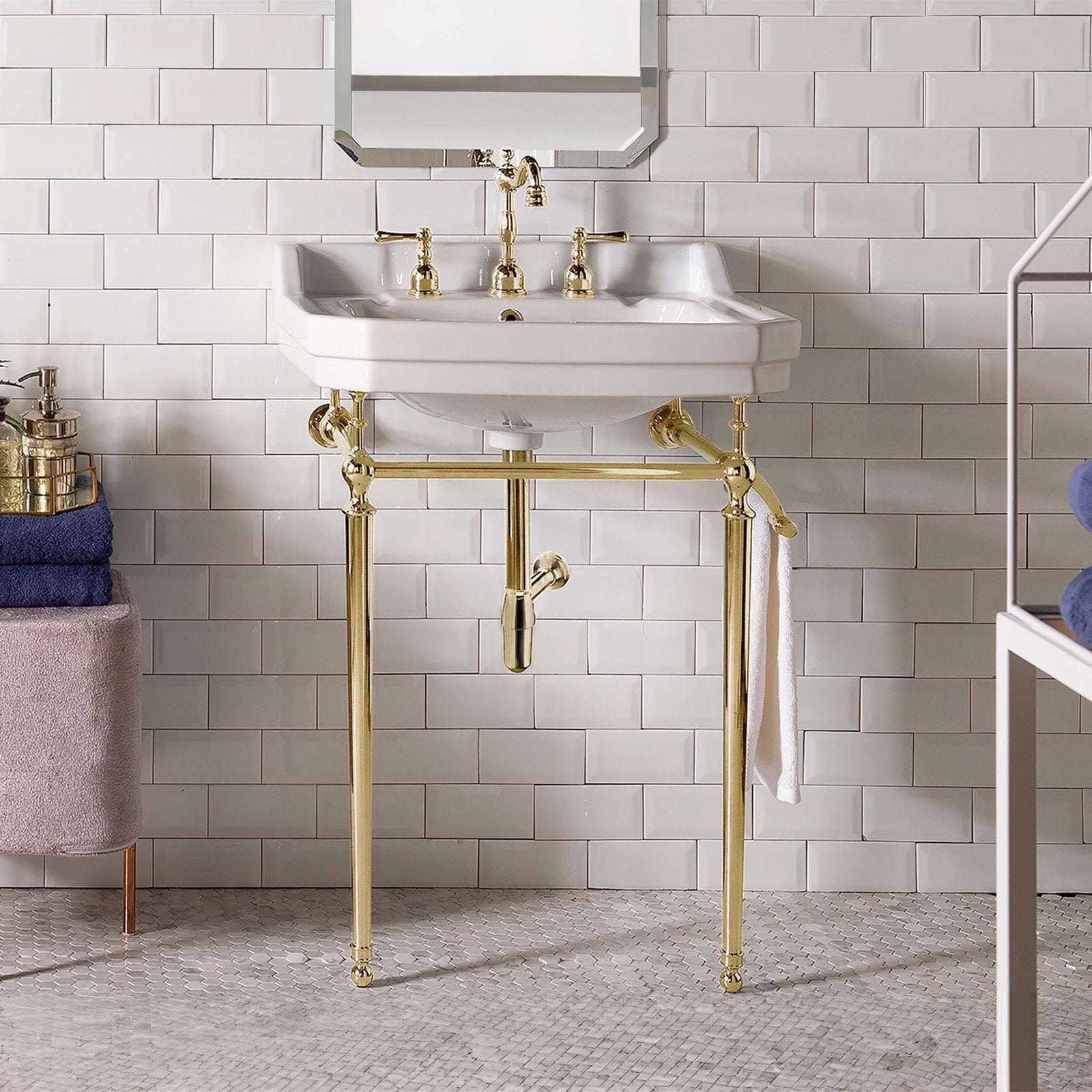 Stone-finish 24-inch ceramic console vanity with a white rectangular basin, polished brass metal legs and fittings, integrated towel bar and exposed brass drain, staged against white subway tile.