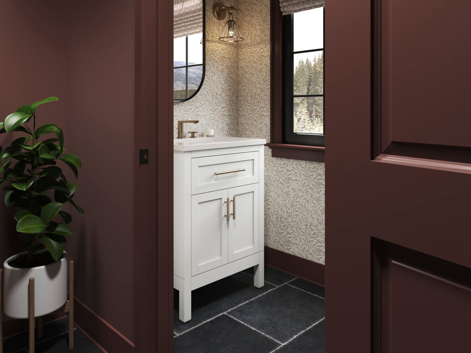White solid-wood 25-inch freestanding single-sink vanity with stone countertop and brass hardware, shown in a modern bathroom with patterned wallpaper, black tile floor, potted plant and burgundy door trim.