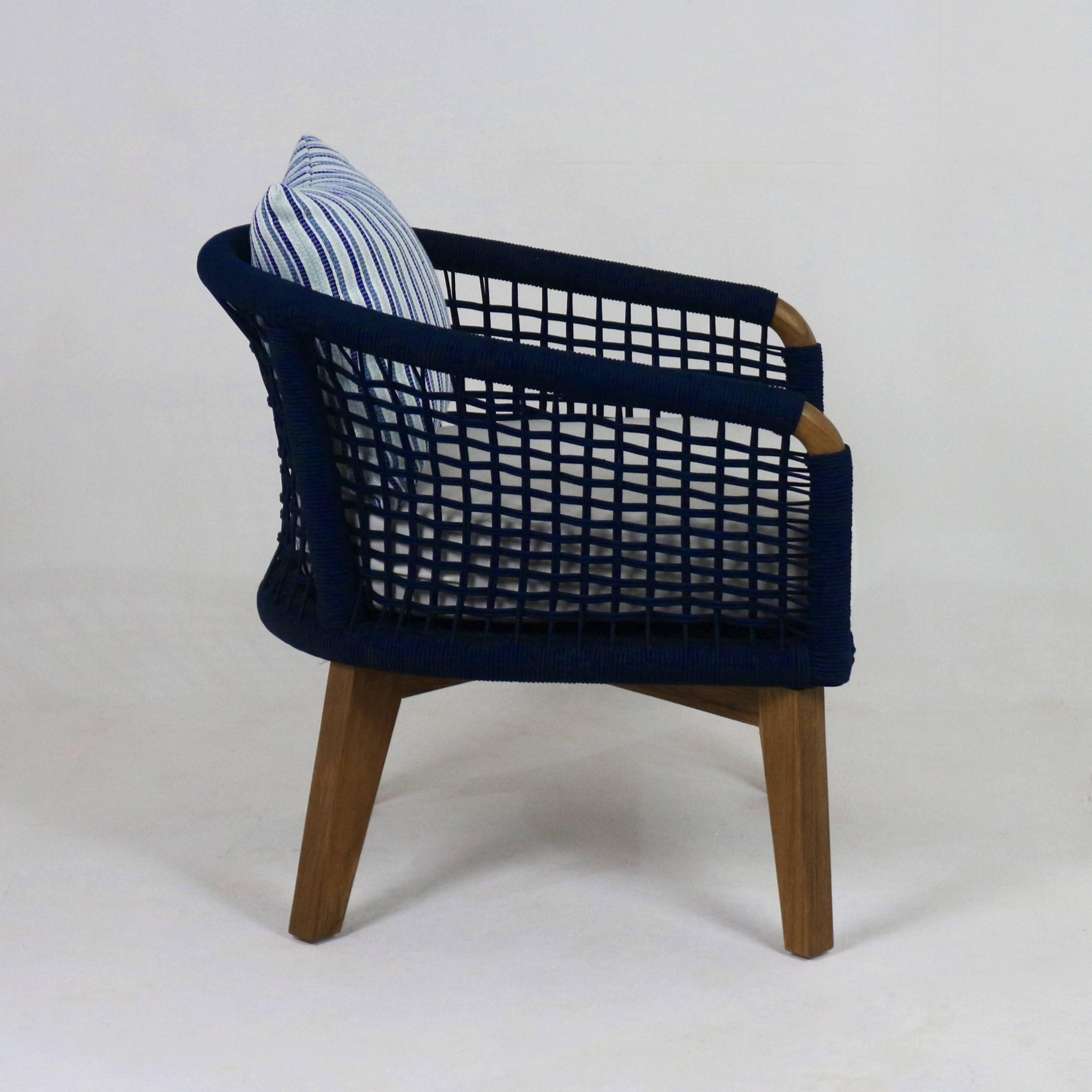 Side view of a modern outdoor lounge chair with navy rope-woven frame, natural wood tapered legs, and a blue-and-white striped fabric cushion.