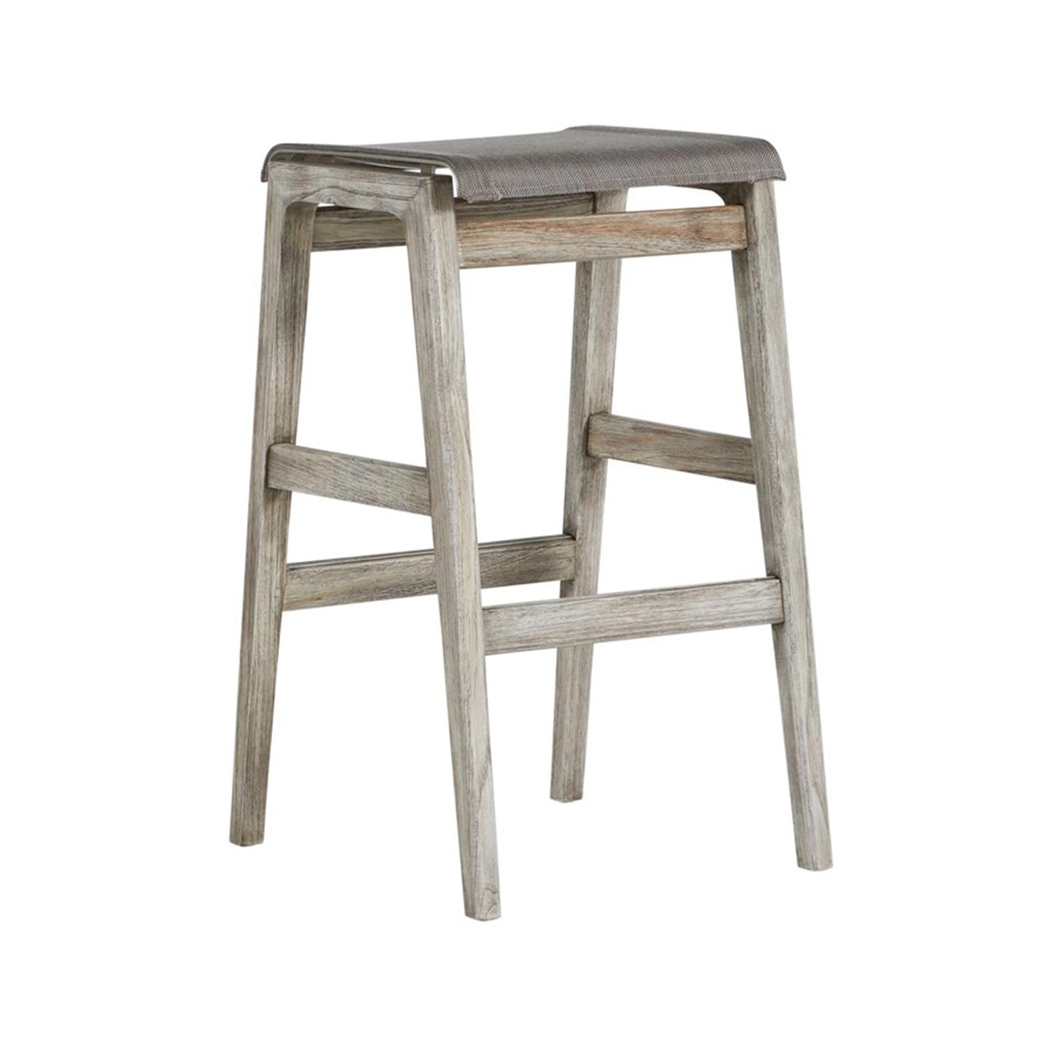 Backless teak outdoor bar stool with natural weathered finish, gray canvas sling seat and slim steel edge, tapered legs and crossbar footrest in a coastal contemporary design.