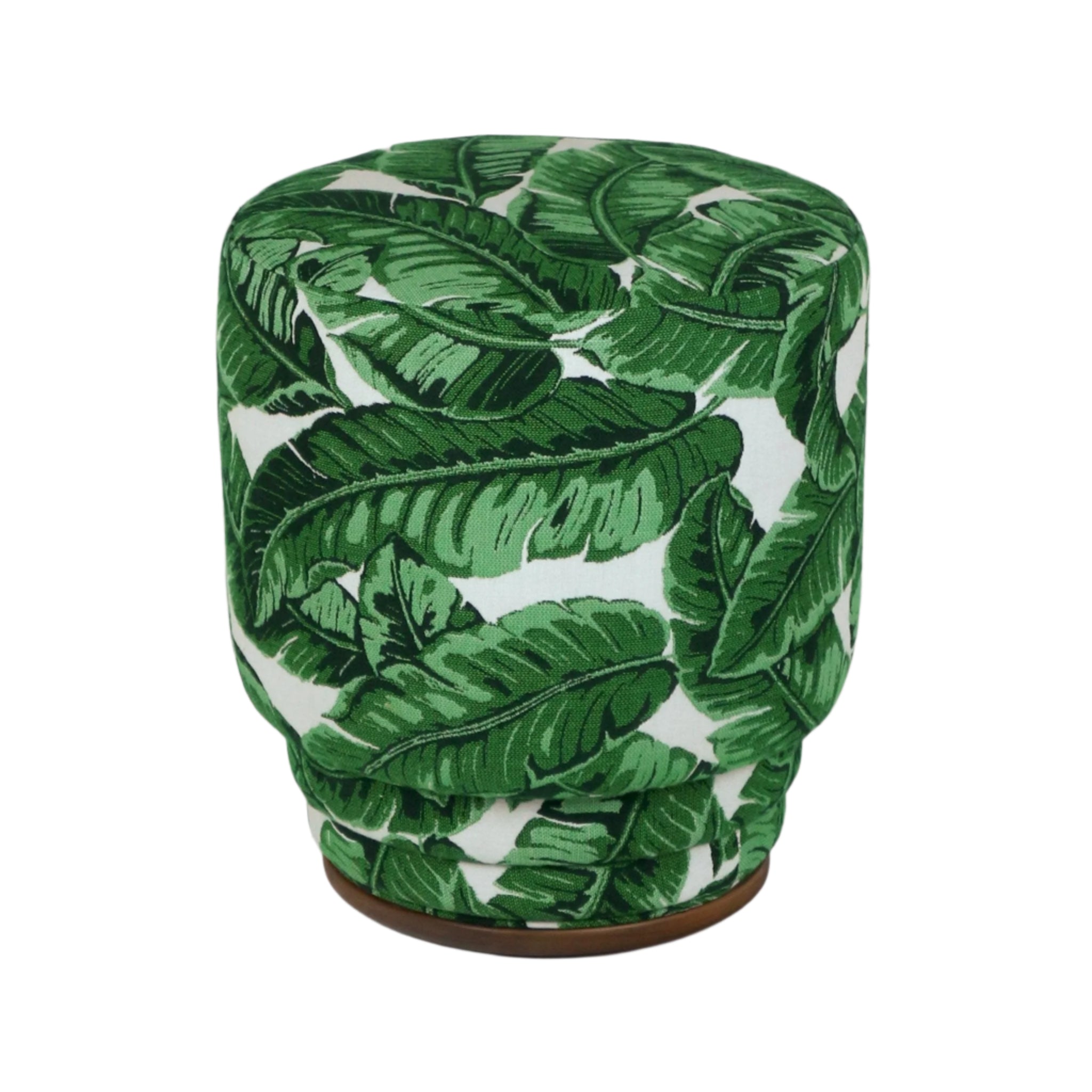Round upholstered ottoman in green tropical leaf print on white fabric, with a cushioned top, gathered sides and a low wooden base — a modern fabric-and-wood piece for indoor or outdoor living spaces.