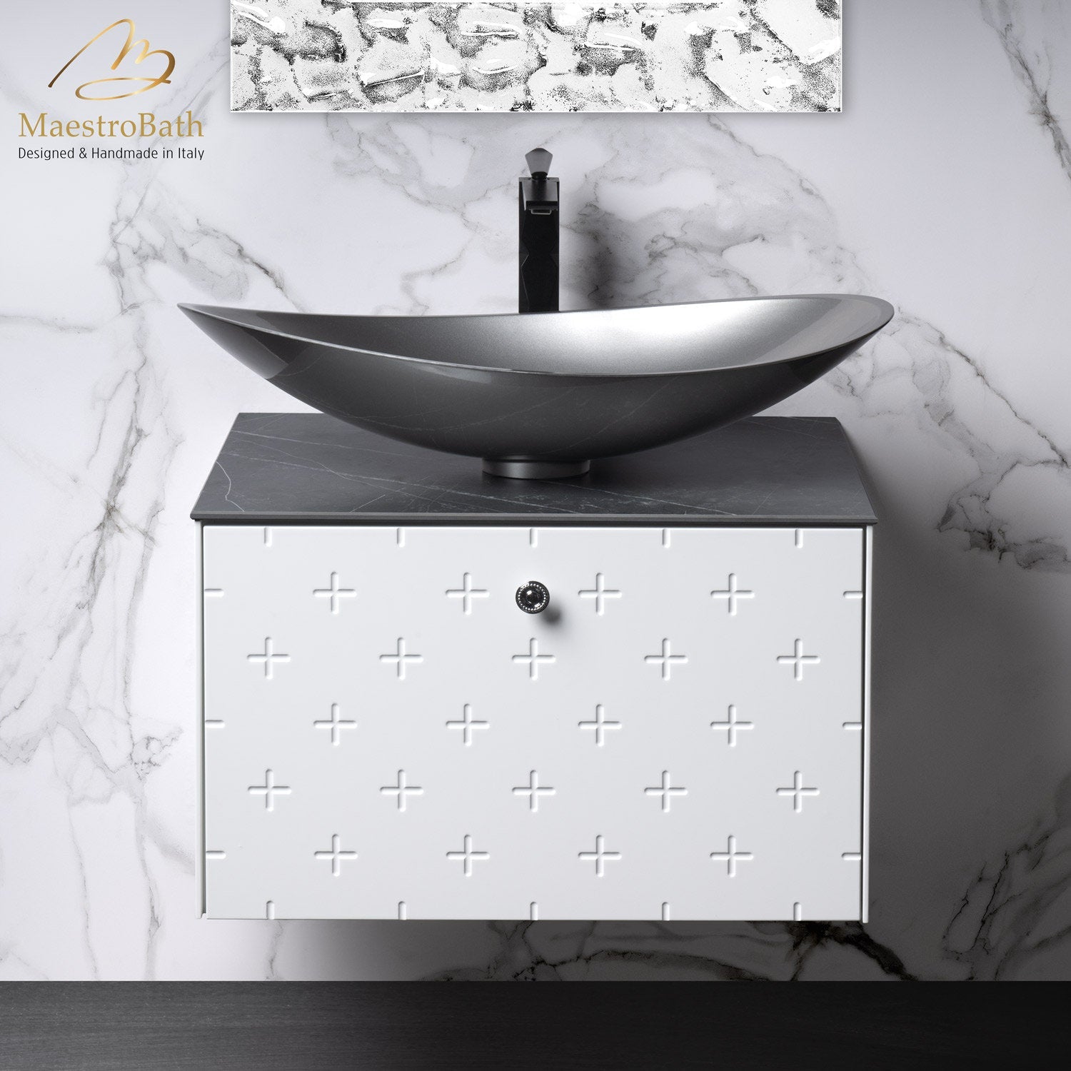 Modern solid-wood, stone-top 24-inch floating bathroom vanity in white with an embossed plus-pattern drawer, dark gray stone countertop, gray vessel sink and matte black faucet against a marble wall.