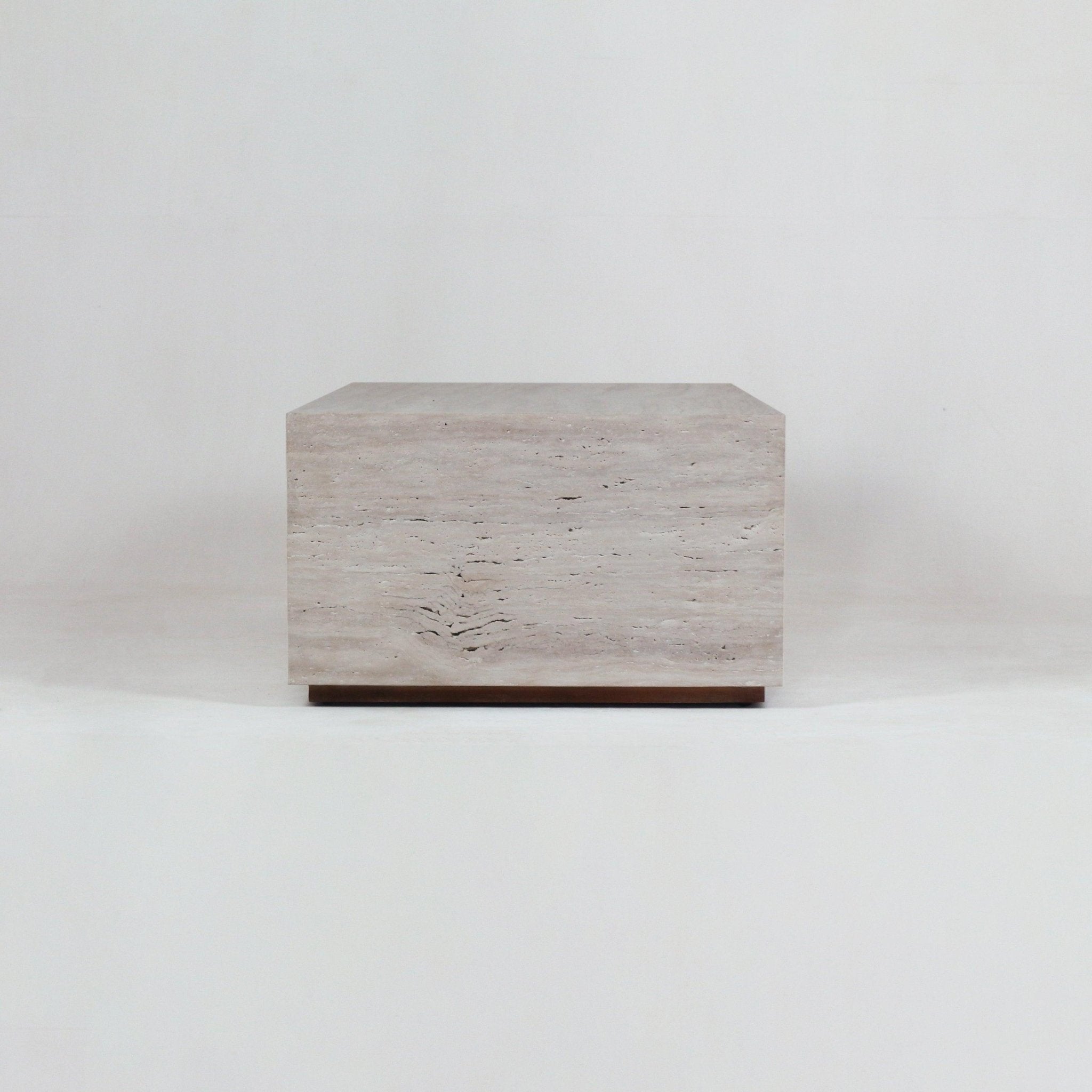 Minimalist rectangular coffee table in natural beige travertine with horizontal veining, sitting on a slim wooden base against a plain white studio background.