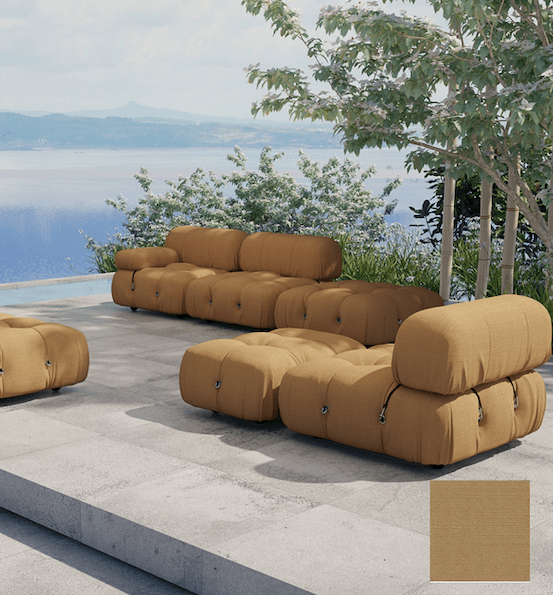 Tan fabric modular outdoor sectional with tufted, low-profile cushioned modules and visible zipper-button hardware, shown with ottoman pieces on a stone patio overlooking water and trees; fabric swatch inset.
