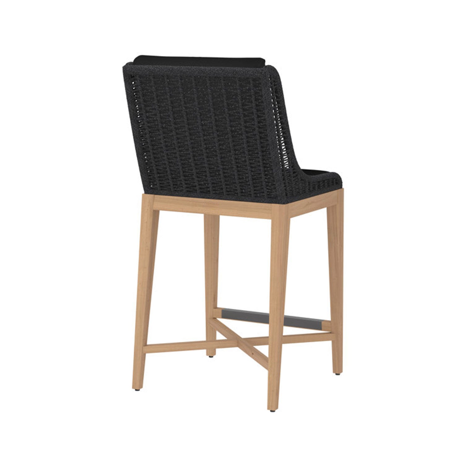 Rear view of an armless outdoor bar stool with a natural teak wood frame, black woven rope back, cushioned black seat and a dark metal footrest.
