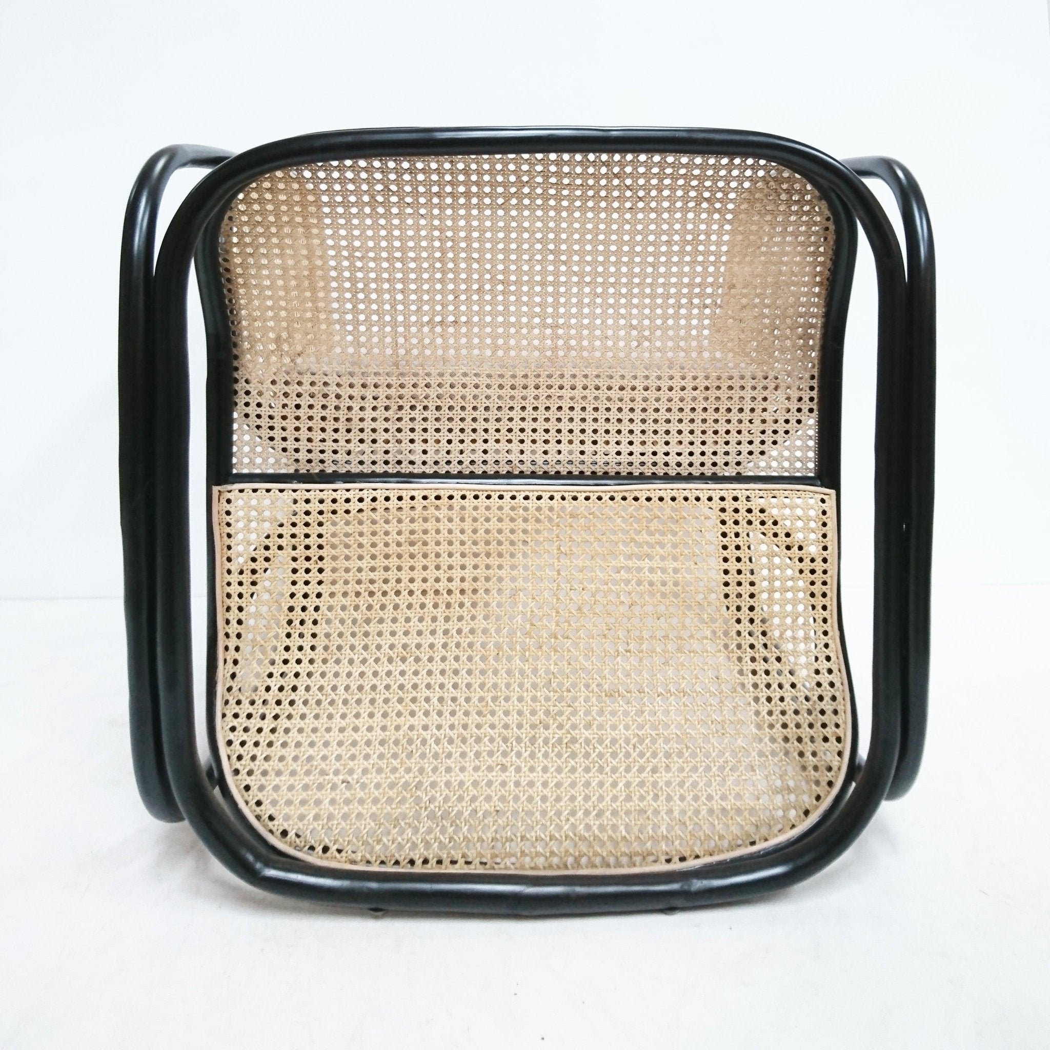 Front view of a modern lounge chair with natural cane woven seat and back set in a black tubular metal frame with curved arm supports.