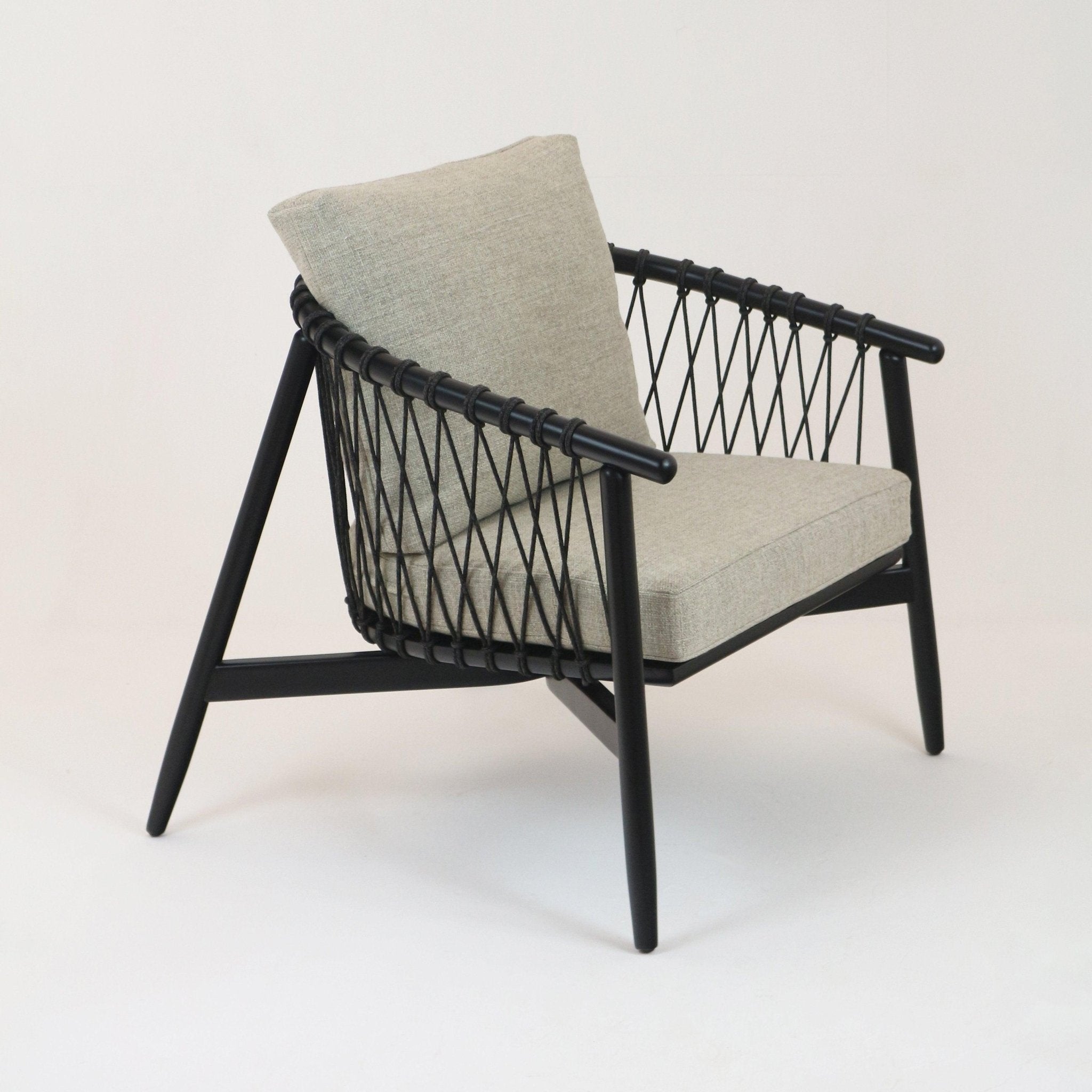 Modern lounge chair with a black solid wood frame and rope-woven sides, upholstered in beige alpaca boucle with a cushioned seat and full back, angled legs and an open contemporary silhouette.