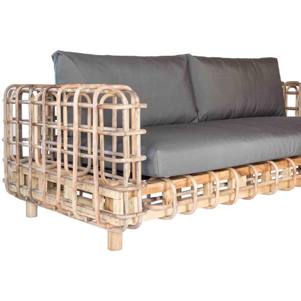 Natural rattan-framed boho sofa with open woven grid arms and base, fitted with thick gray fabric seat and back cushions.