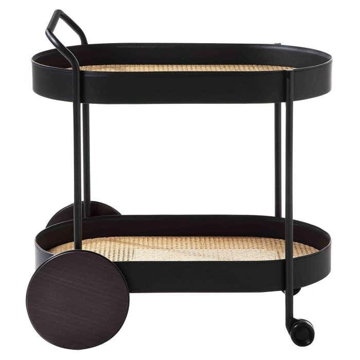 Modern two-tier bar cart with a matte black metal frame, woven rattan cane shelves, integrated handle, oversized round wooden rear wheels and a front caster for easy rolling.