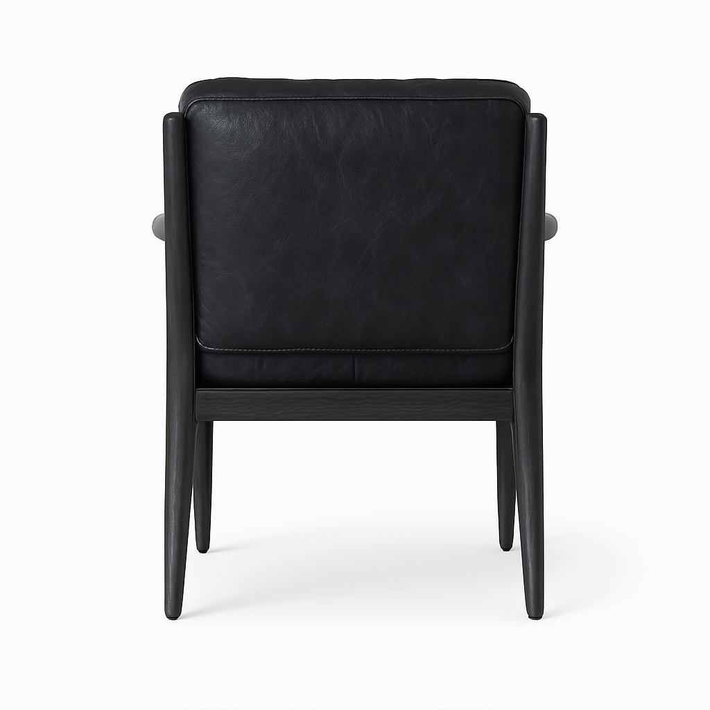 Rear view of a dining chair upholstered in aged black nubuck leather, showing a padded back, slim rounded arm supports and tapered walnut wood legs in a mid-century modern silhouette.