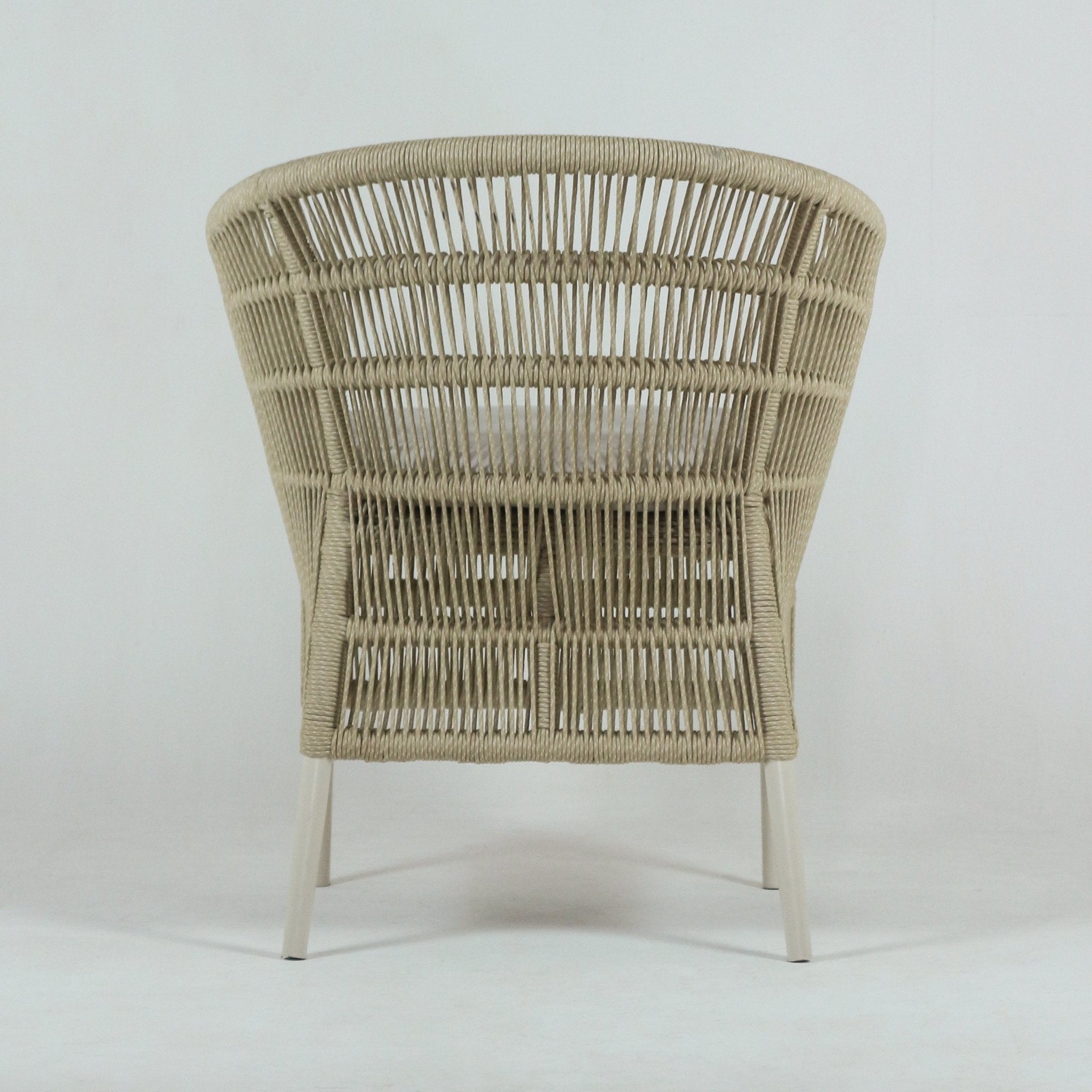 Back view of a coastal outdoor patio chair featuring light beige rope weave, a cushioned seat visible through the weave, and slim white metal legs.