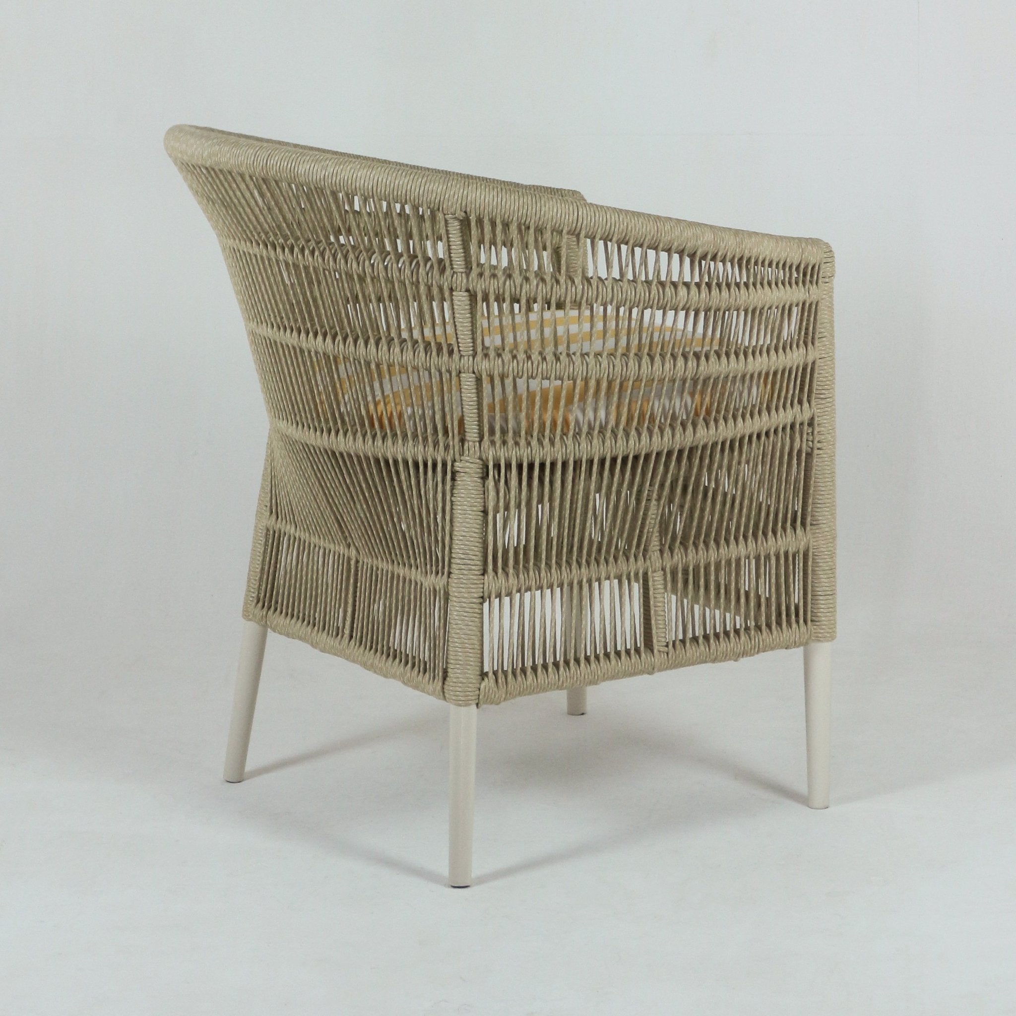Back three-quarter view of a coastal outdoor patio armchair with a beige rope-wrapped frame, white metal legs and a cushioned seat covered in light yellow striped fabric.