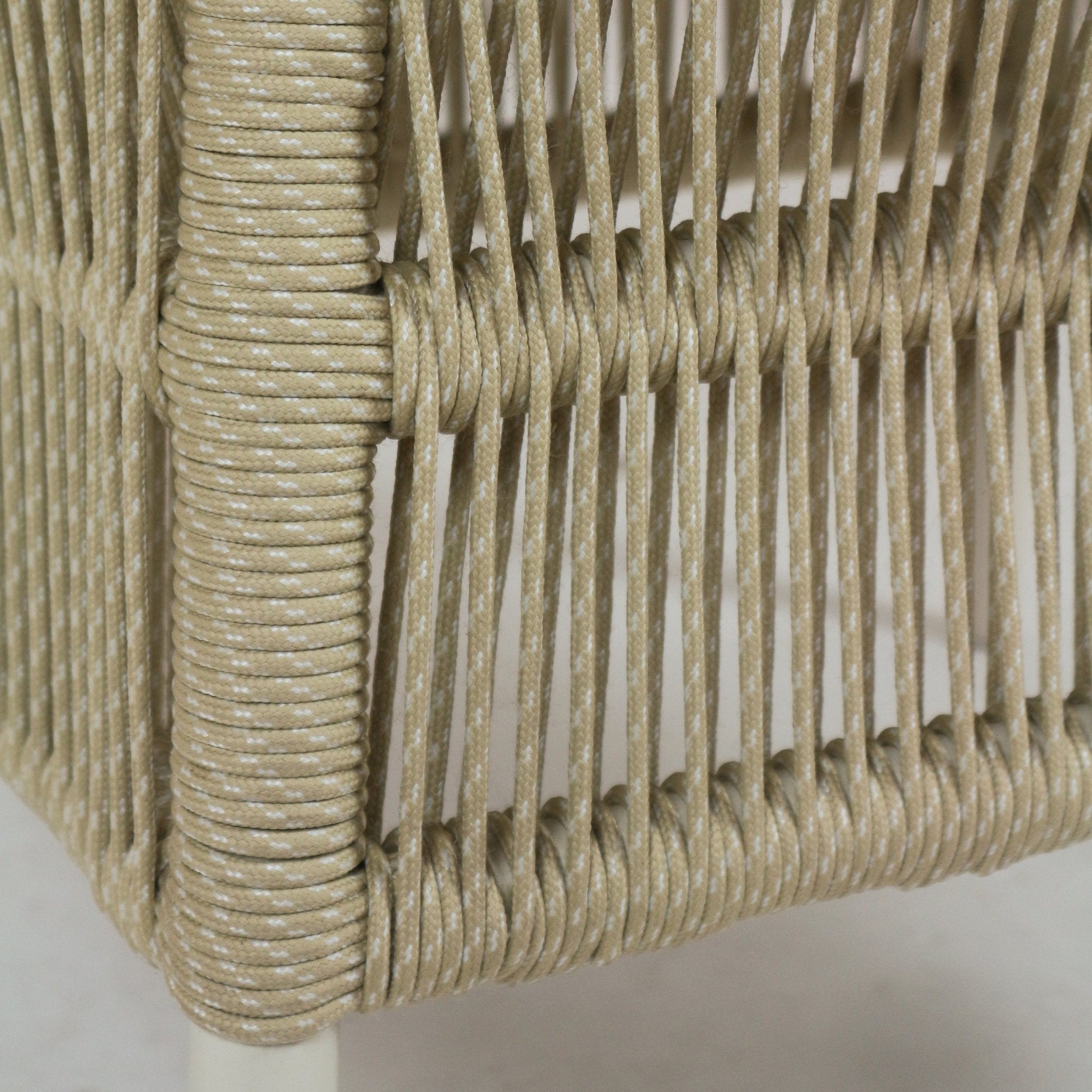 Close-up of beige rope cord tightly wrapped around a metal patio chair frame, showing vertical braided rope strands with white flecks and a textured coastal look.