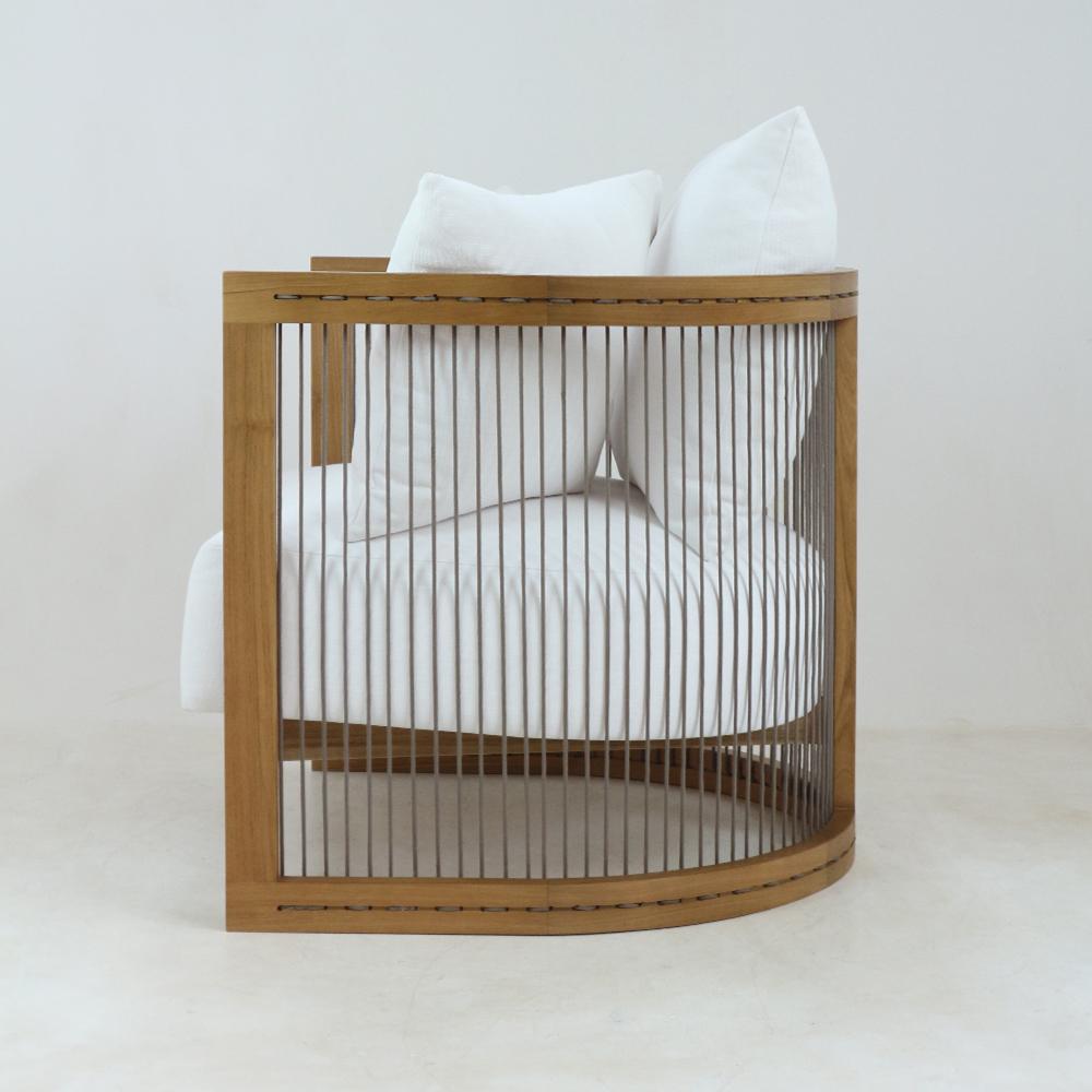 Side view of a modern lounge chair with a curved natural solid-wood frame and vertical woven rope slats, upholstered in white fabric with plush seat and back cushions.