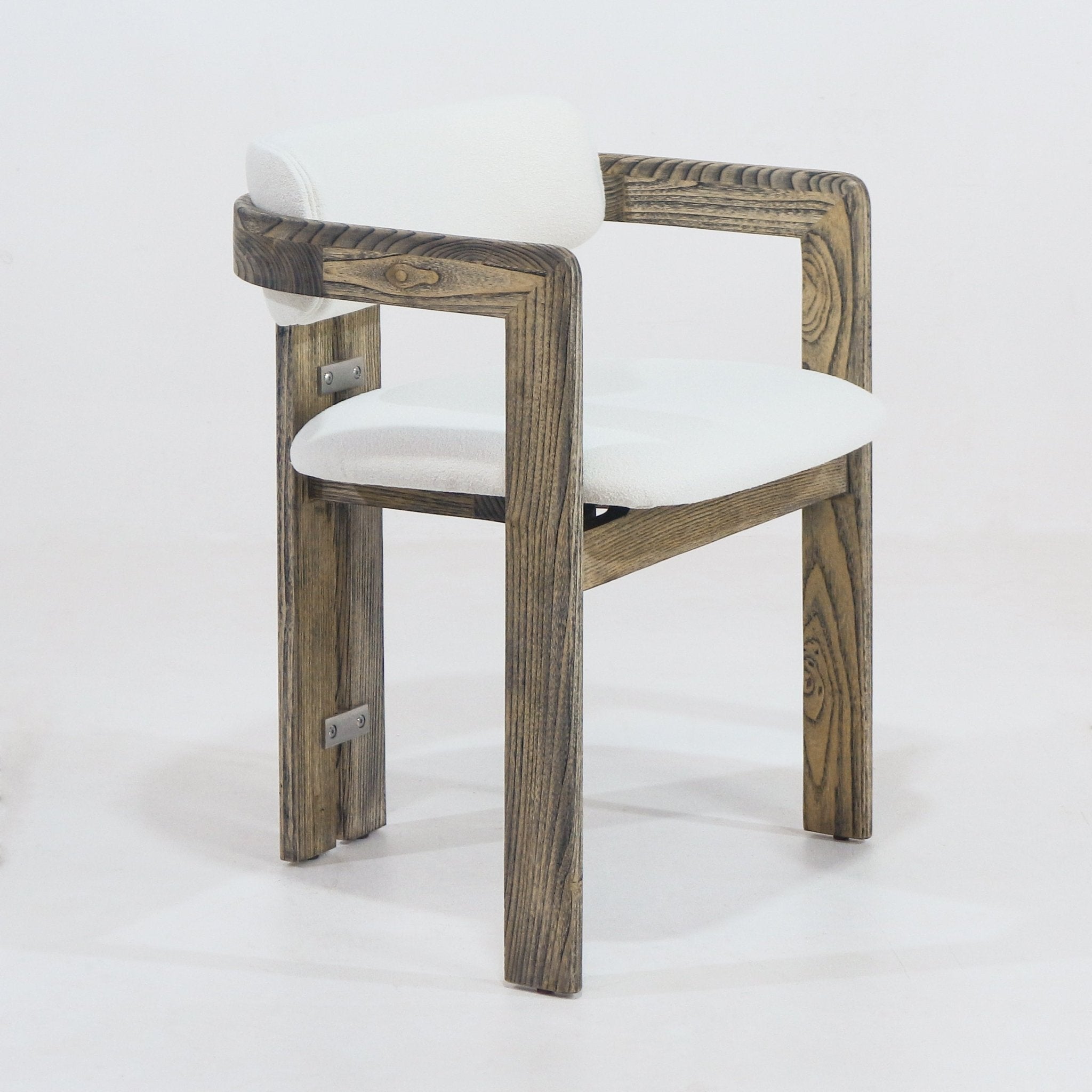 Rustic brown natural-wood dining chair with a cream boucle upholstered seat and low rounded backrest, squared wooden arms showing pronounced grain and visible metal brackets on the inner legs.