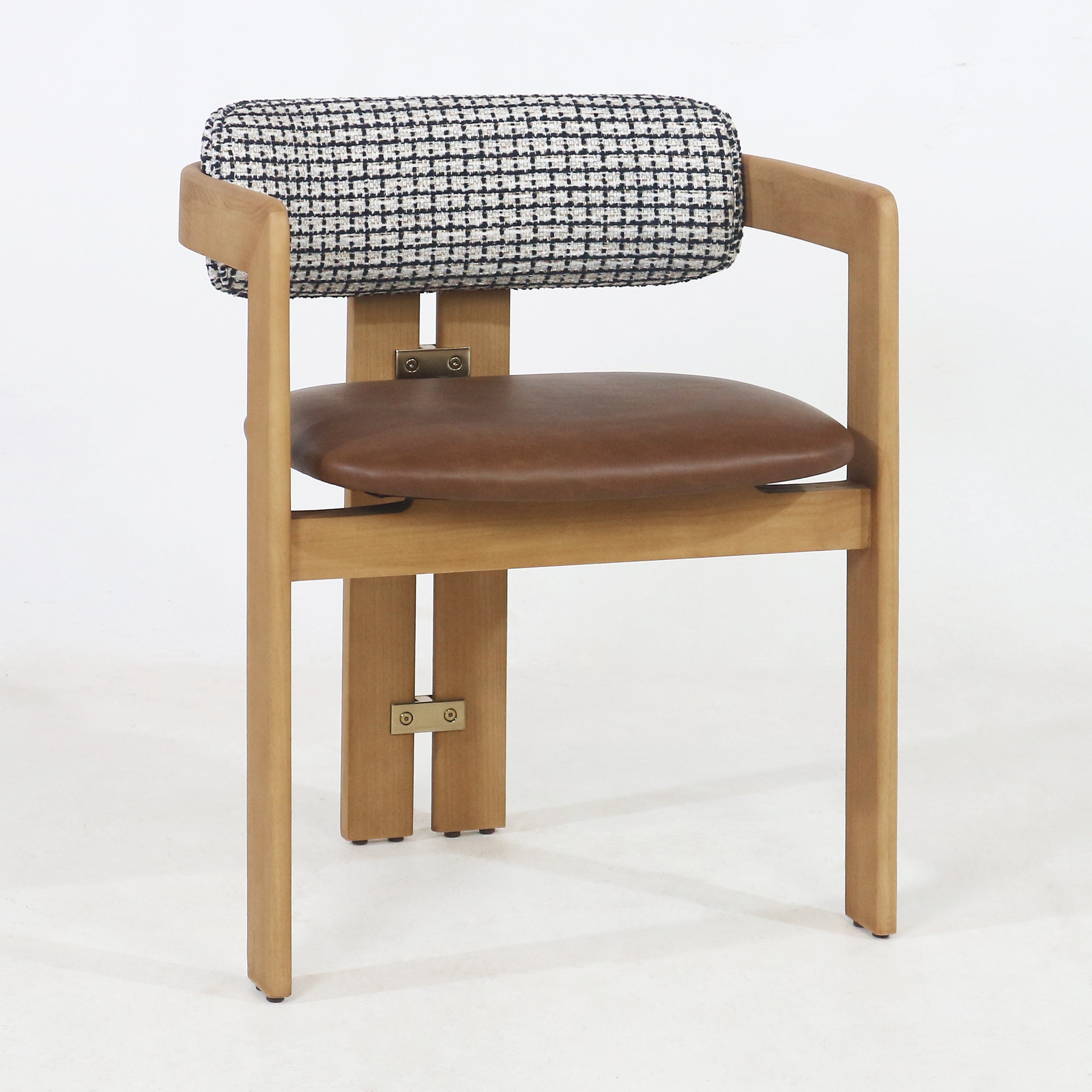 Mid-century modern teak dining chair with a rounded brown leather seat, black-and-white tweed cylindrical back cushion, open wooden arms and visible brass hardware accents.
