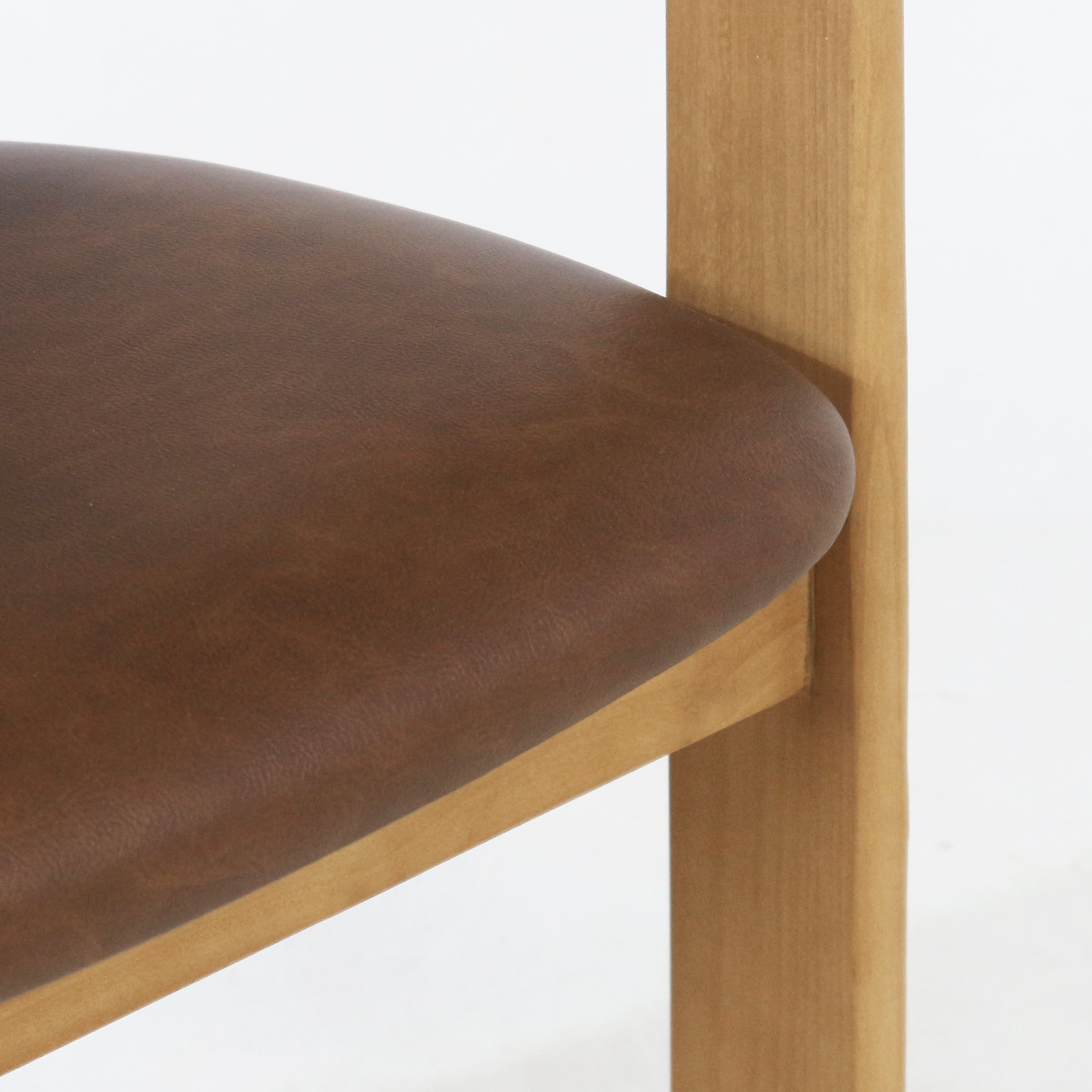 Close-up of a rounded brown upholstered dining chair seat with a light teak wood frame and vertical leg, highlighting the fabric texture and smooth seat edge.
