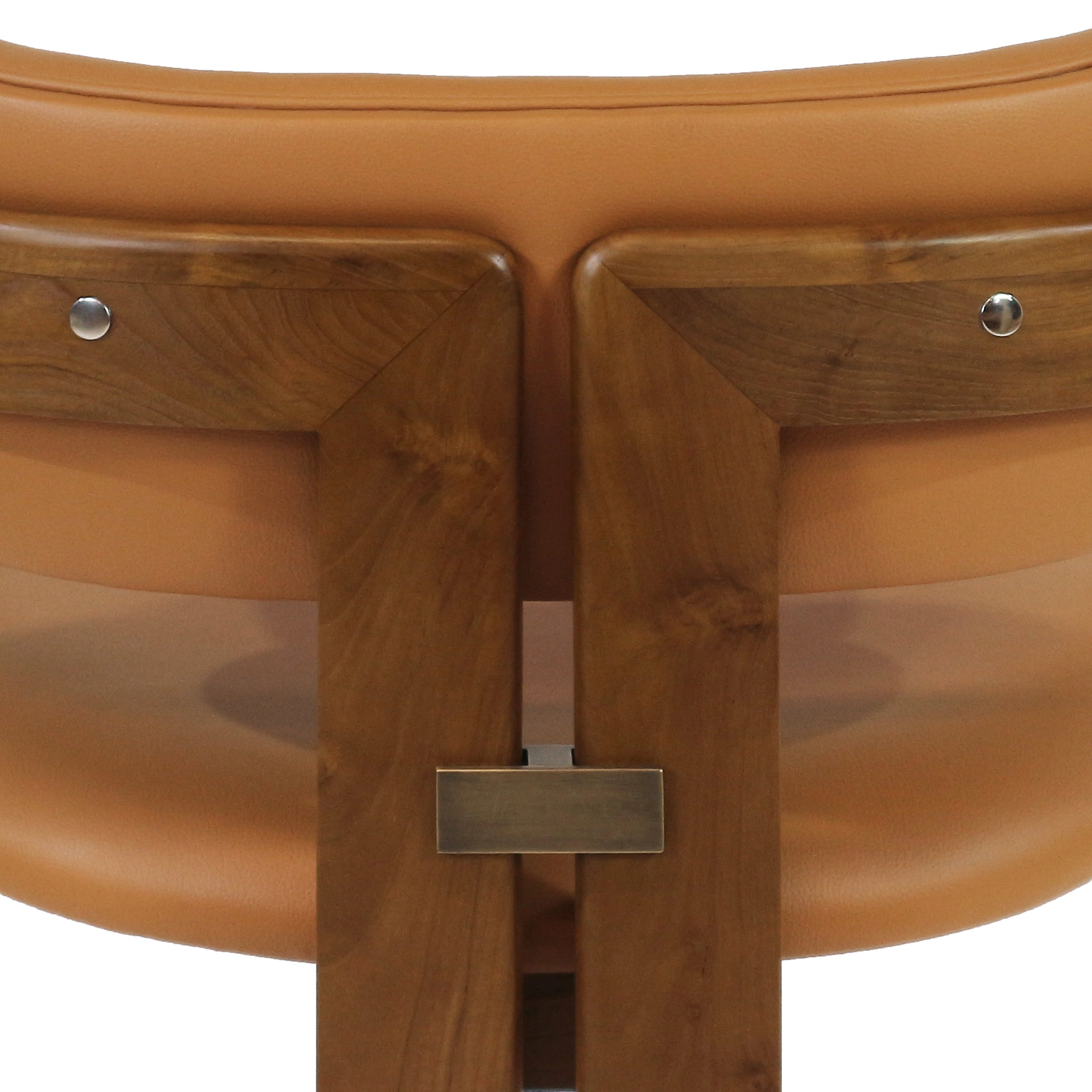 Close-up of a walnut dining chair back showing tan nubuck leather upholstery, warm walnut wood grain, two round metal fasteners and a rectangular brushed metal connector joining the vertical supports.