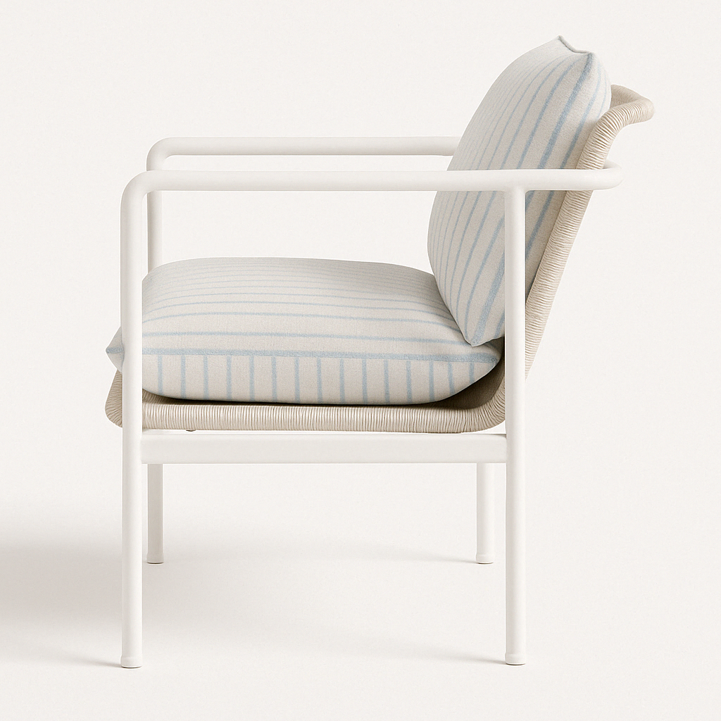 Side view of a coastal outdoor accent chair with a white aluminum frame, beige woven wicker seat support, and cushioned cream fabric seat and back featuring thin light-blue stripes.