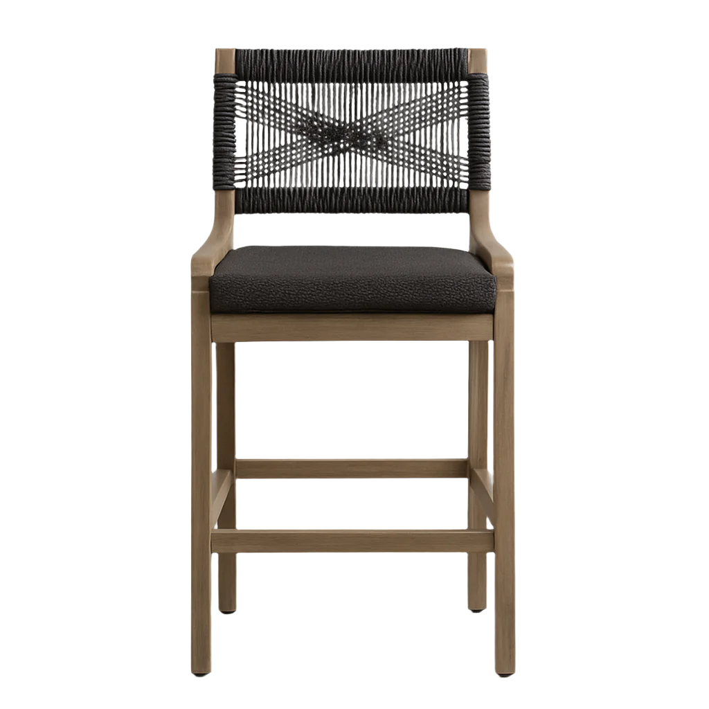 Front view of a natural teak-frame outdoor counter stool with a dark woven rope back in an X pattern and a black textured fabric cushioned seat, straight legs and built-in footrest on a white background.