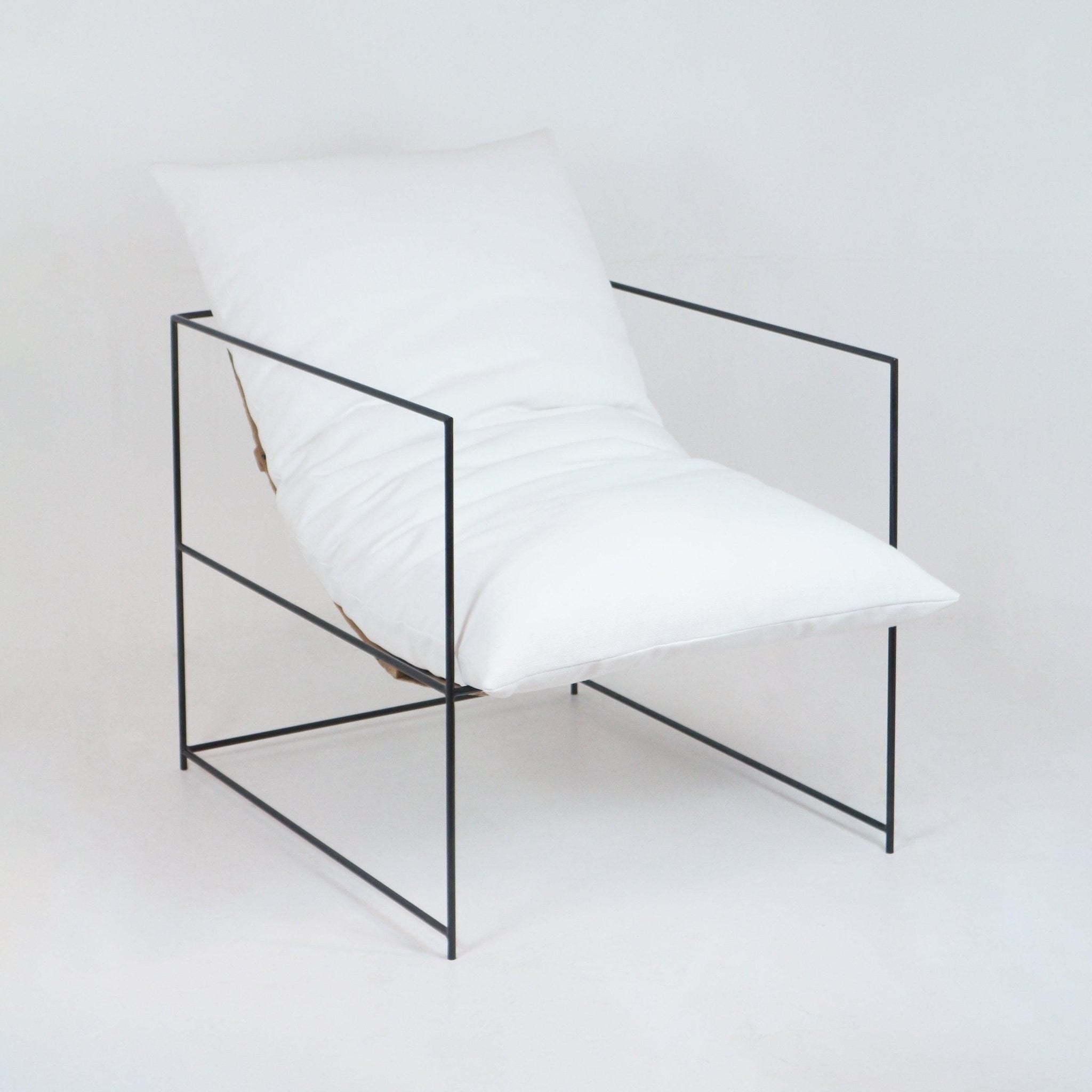 Minimalist lounge chair with a plush white linen cushion and pillow held within a slim black metal frame, low-profile armchair suited for modern or contemporary living rooms.