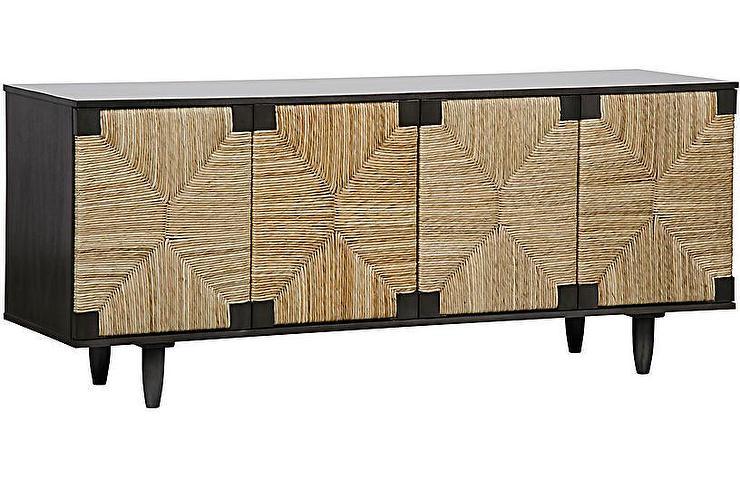 Long coastal sideboard with a dark solid wood frame and four woven seagrass cabinet doors featuring a geometric starburst pattern, raised on tapered legs in natural and black finishes.