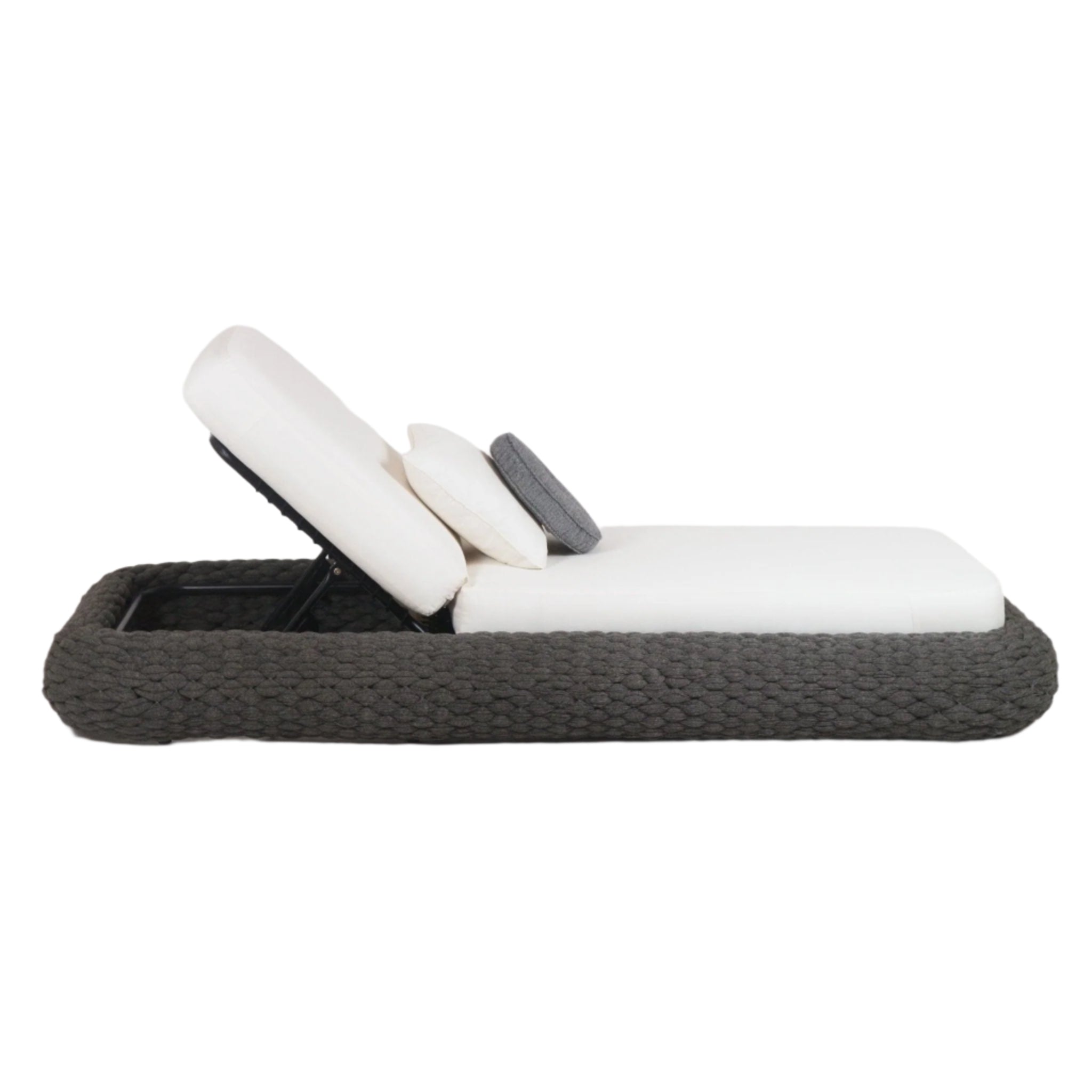 Side view of a poolside chaise lounger with a taupe rope-woven frame, white fabric cushions and an adjustable metal reclining backrest, shown with layered white pillows and a small round gray accent pillow.