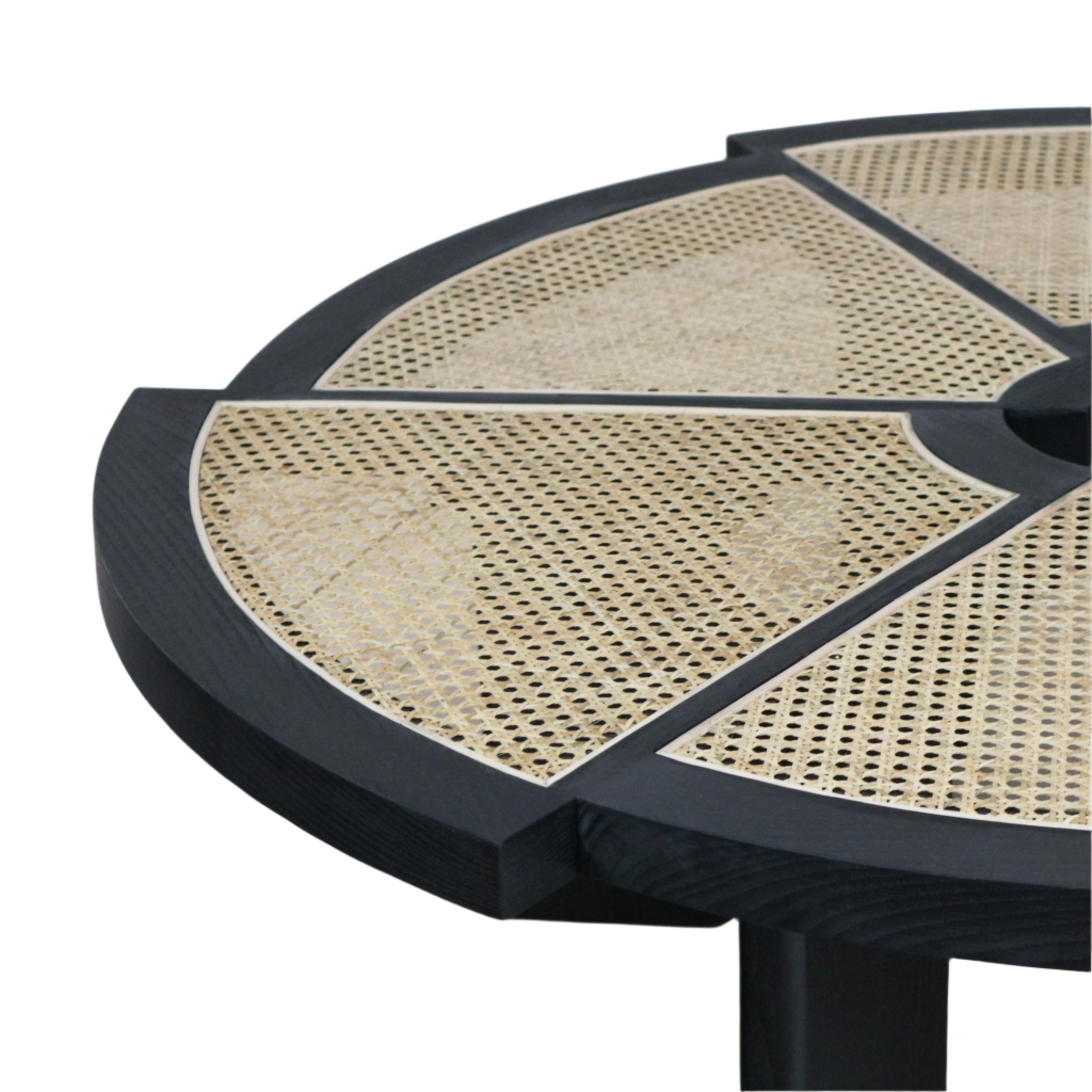 Close-up of a round coffee table top showing a smoked black solid wood frame with natural cane rattan insets arranged as wedge panels and a partial view of the black tapered leg.