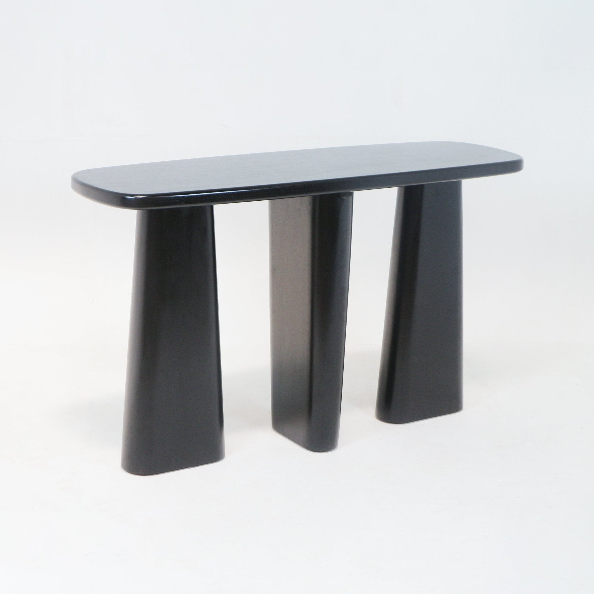 Black solid-wood console table with a rounded oval top and three sculptural tapered pedestal legs, modern minimalist silhouette ideal for an entryway or living room.
