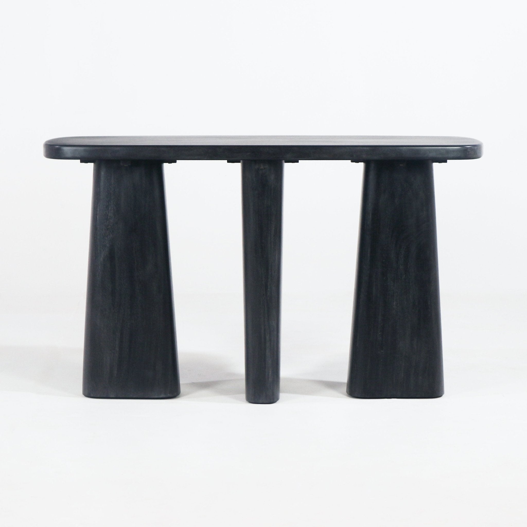 Modern black solid wood console table with a rounded rectangular top supported by two wide tapered pedestal legs and a central cylindrical leg, shown on a plain white background.