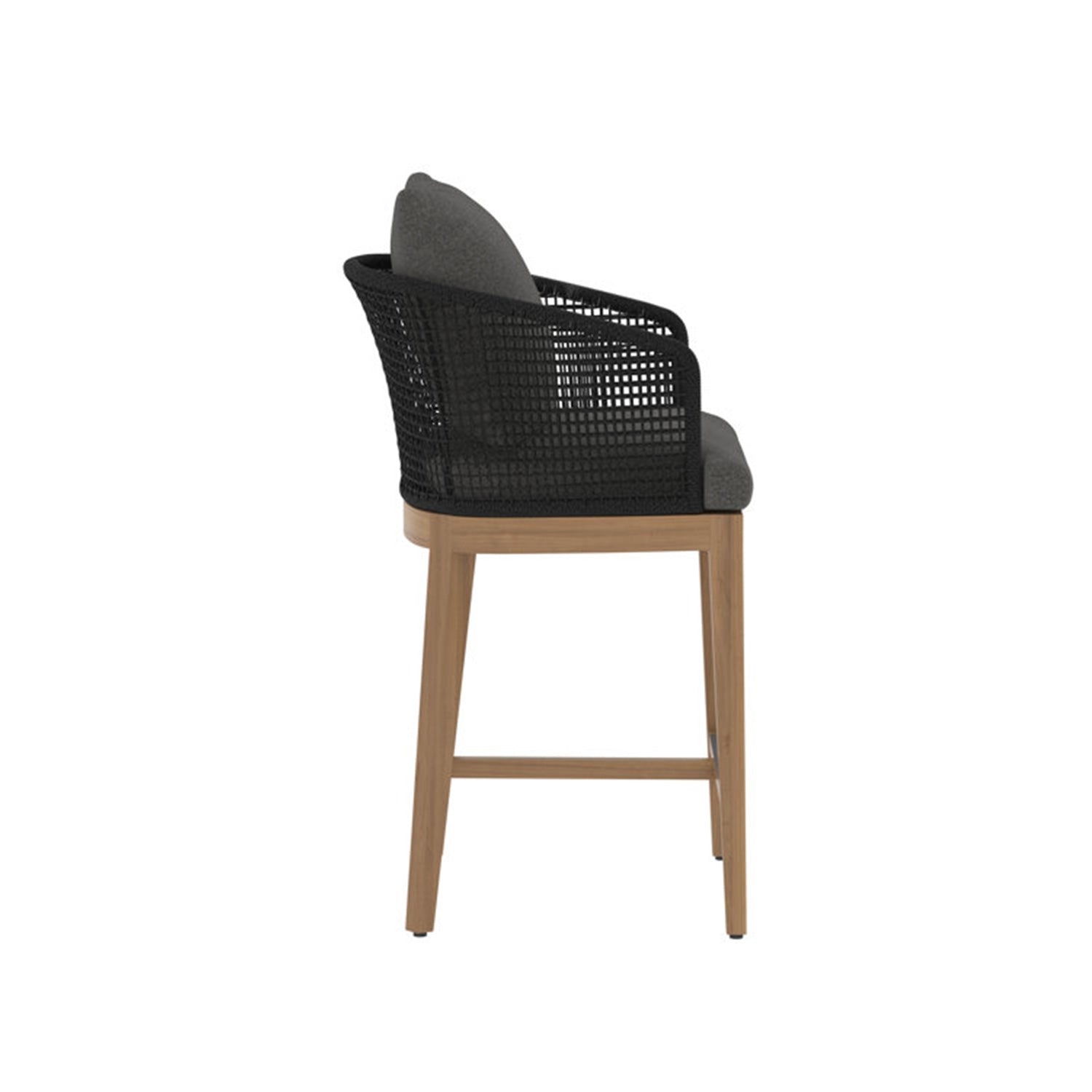 Side profile of a teak outdoor bar stool featuring a natural teak wood frame, black woven back and armrests, and gray fabric upholstered seat and back cushion with counter-height legs and a front footrest.