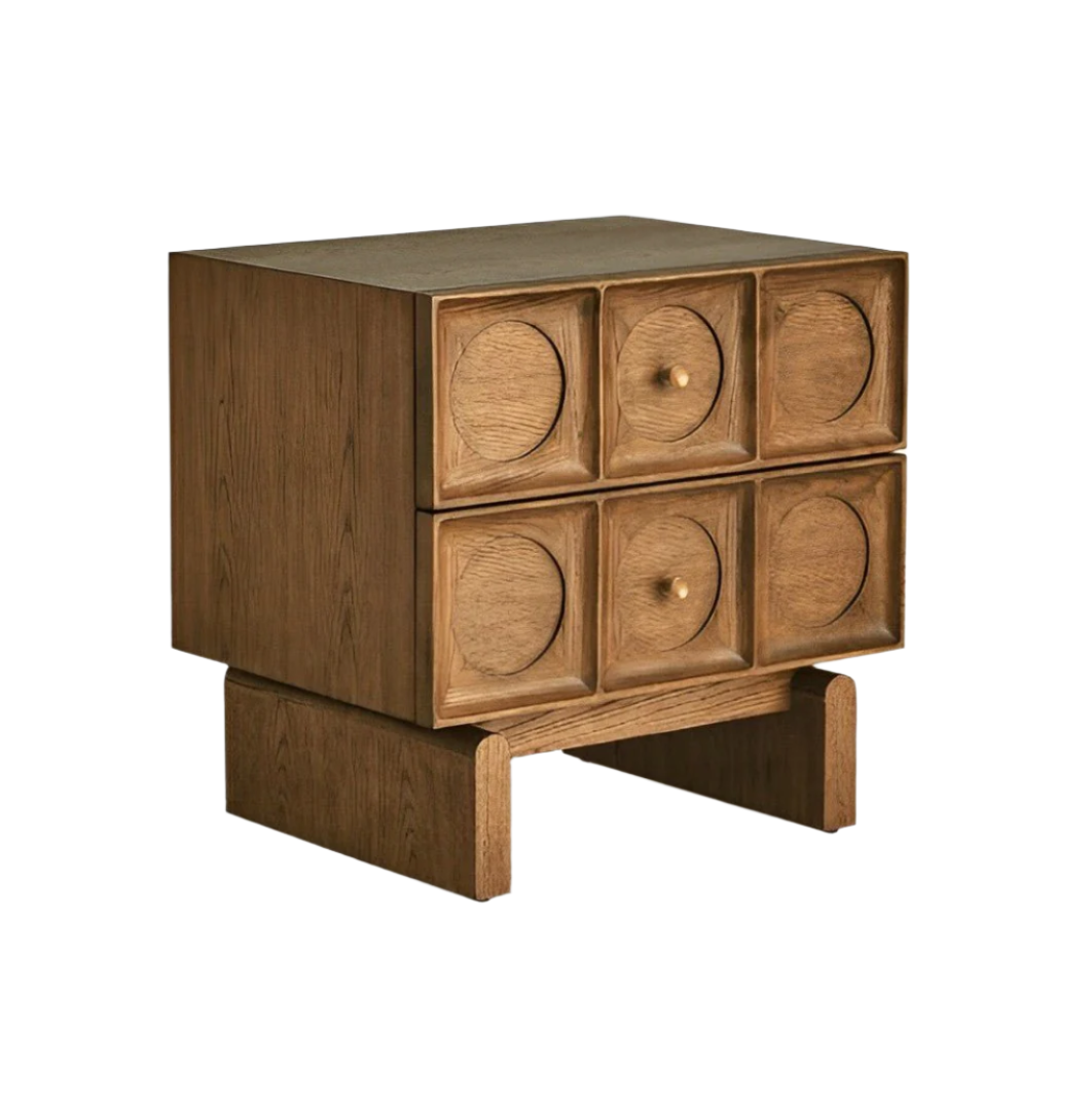Solid wood nightstand in a natural brown finish with two rows of three carved circular drawer fronts, small round knobs, and raised open-base block legs; contemporary glam bedside table.